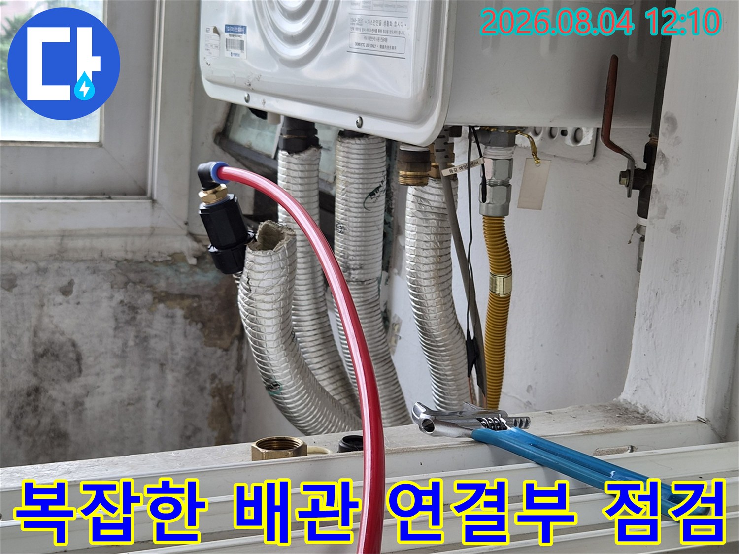 보온재를 씌운 여러 개의 배관과 파란색 손잡이의 몽키스패너가 놓인 작업 현장