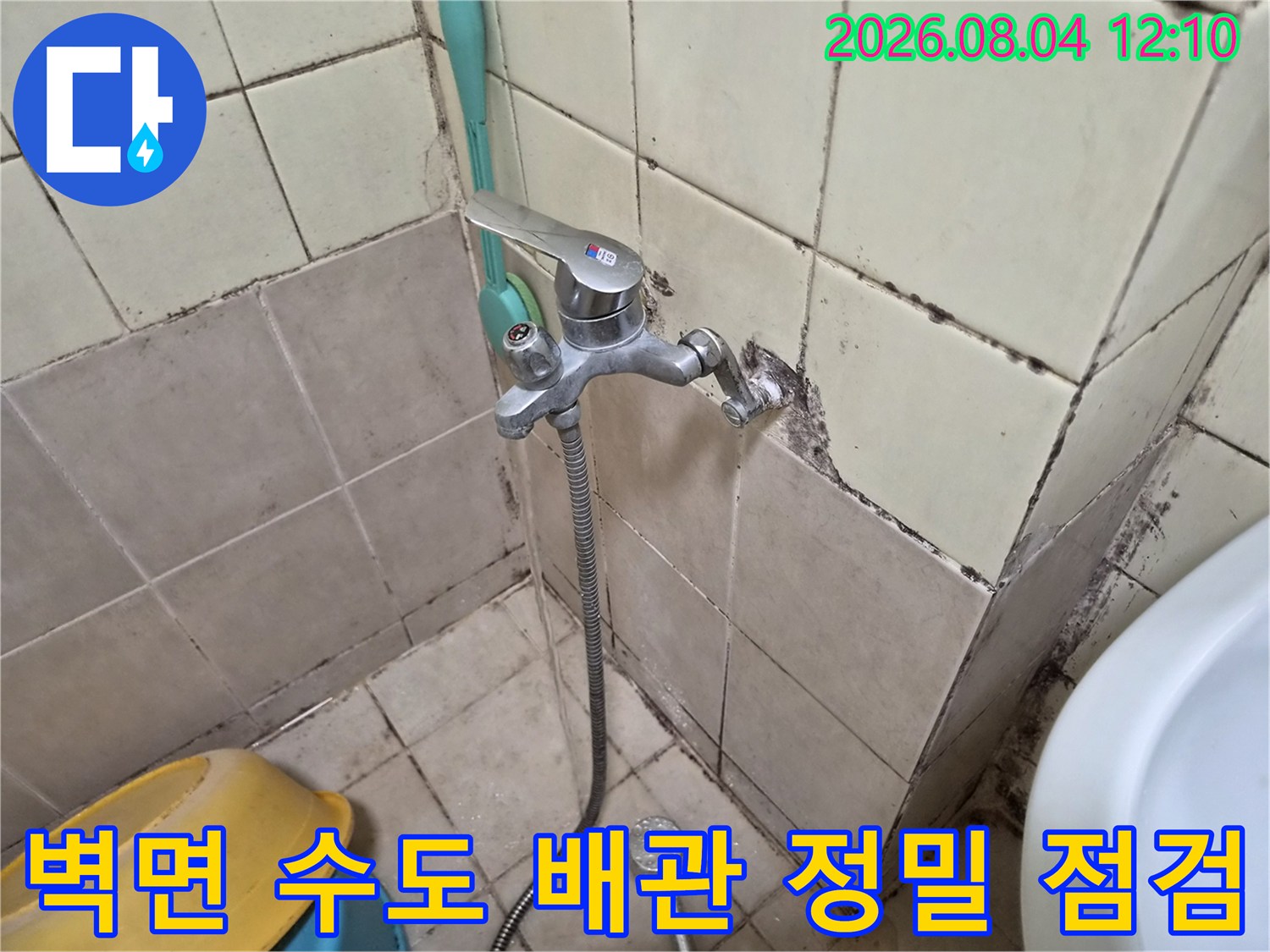 화장실 벽면에 설치된 수전과 연결 배관의 상태를 면밀히 검사하는 모습
