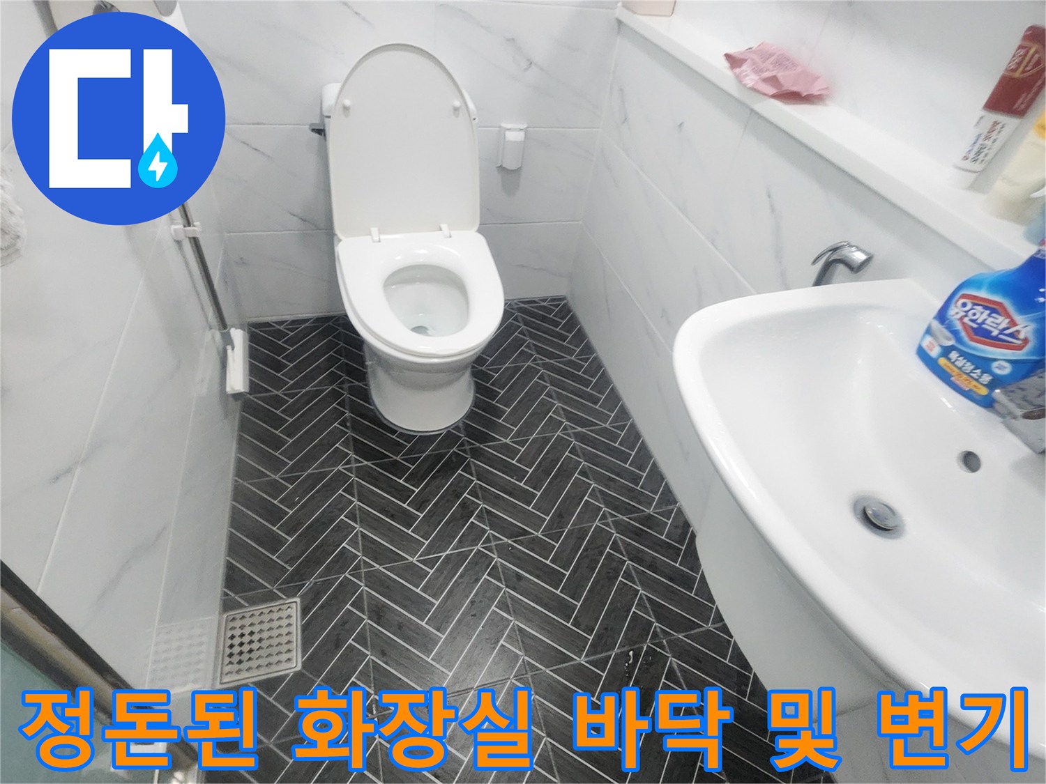 헤링본 패턴 타일과 흰색 도기 제품이 설치된 화장실