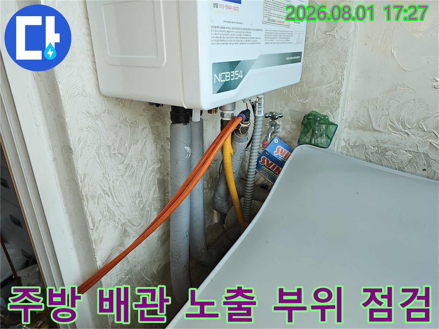 싱크대 밑에 위치한 가스 계량기와 온수 및 냉수 배관의 연결 상태를 세밀하게 살피는 장면