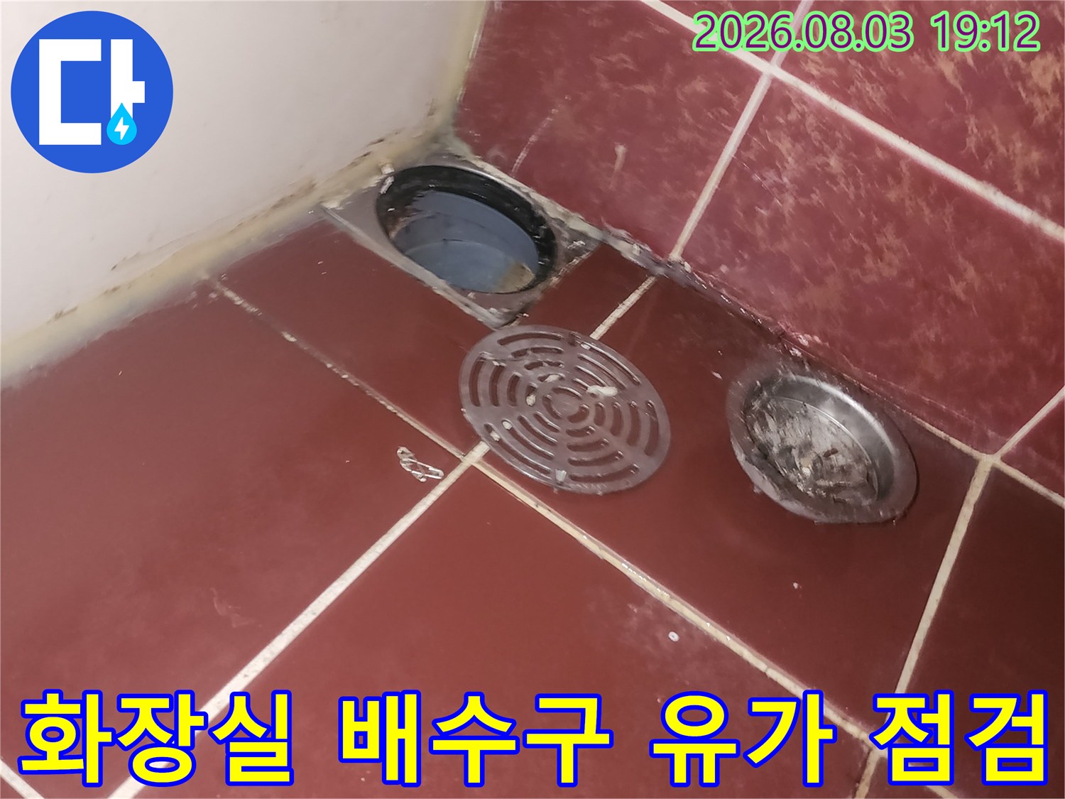 화장실 바닥에 설치된 금속 재질의 배수구 유가와 타일 마감 상태