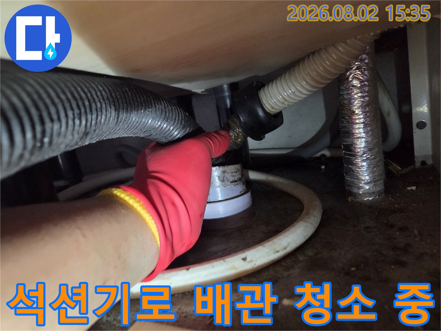 싱크대 아래 배수 호스 연결부에 석션 장비를 사용하여 이물질을 제거하는 모습