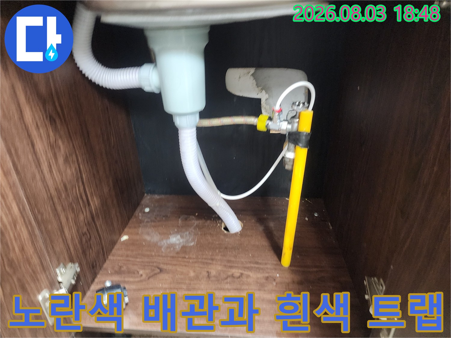 싱크대 하부 공간 내 설치된 노란색 관과 유연한 배수 호스