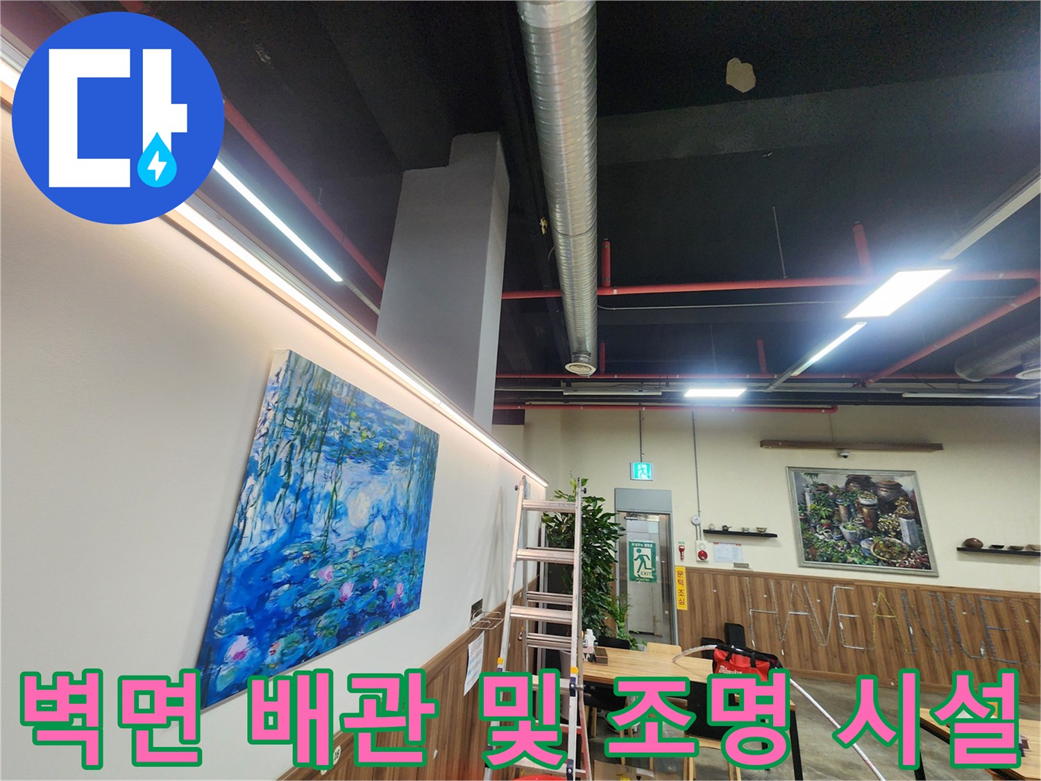 천장의 긴 금속관과 벽면에 설치된 밝은 조명이 비치는 현장 모습입니다.