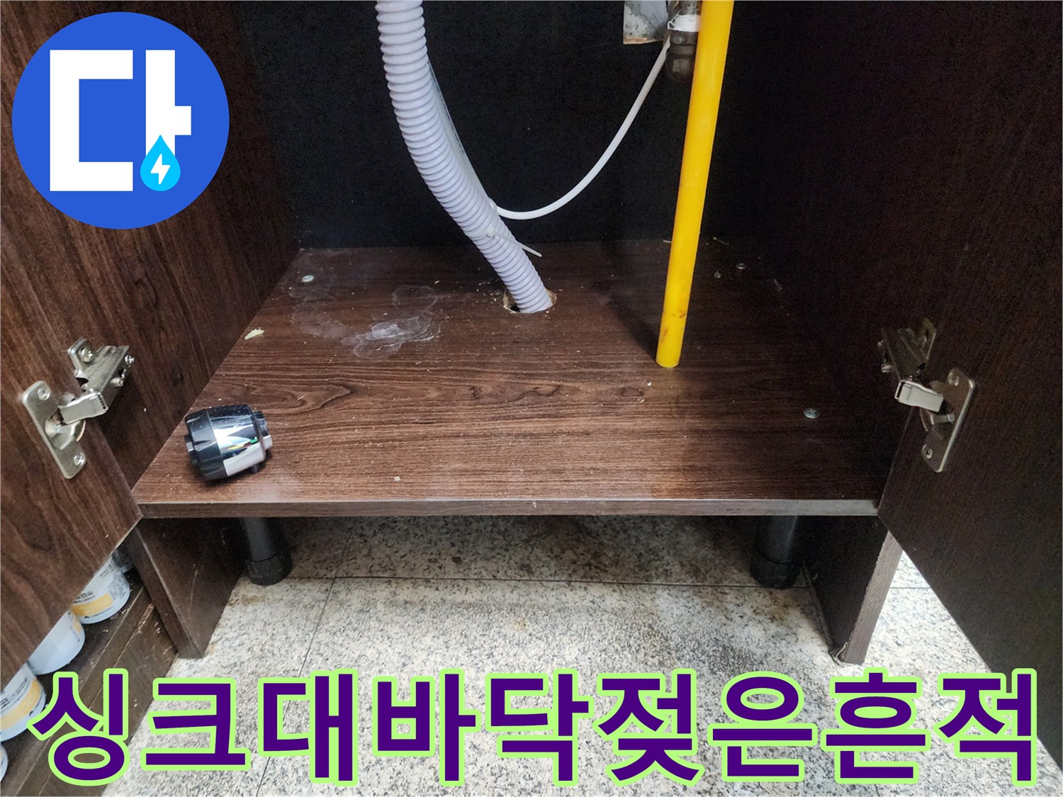 축축하게 젖어있는 싱크대 하단 나무 판넬과 배관들