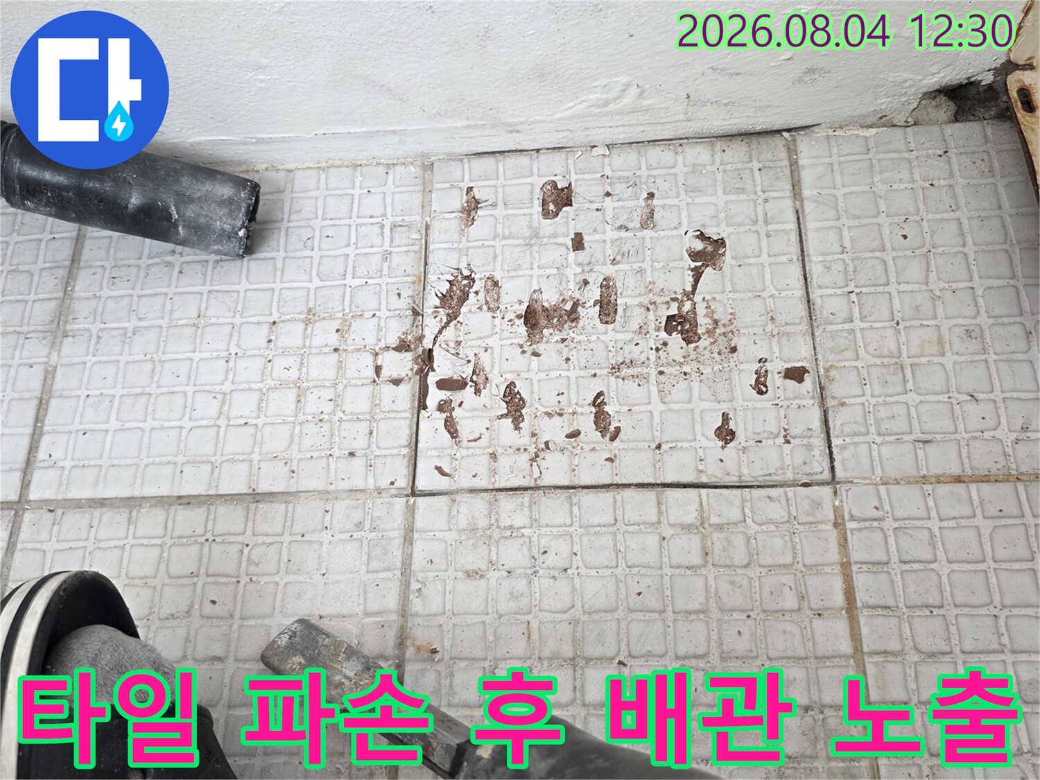 파손된 타일 내부를 굴착하여 드러난 온수 배관과 작업 도구
