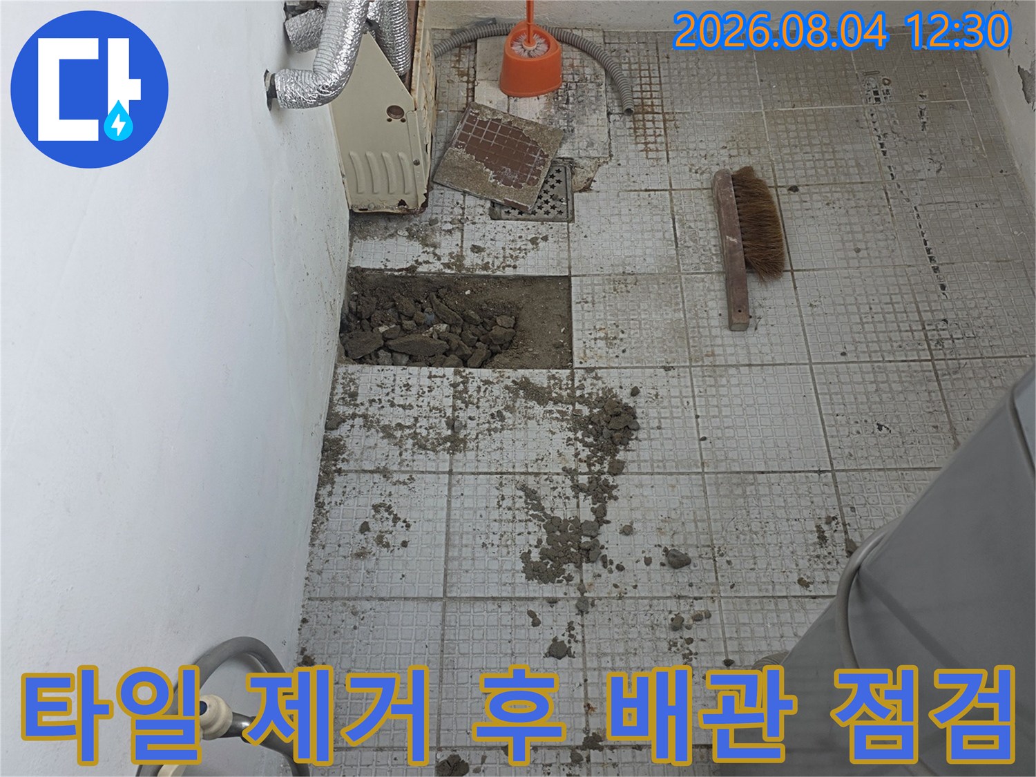 파손된 타일 벽면과 노출된 배관을 점검하는 누수 공사 현장
