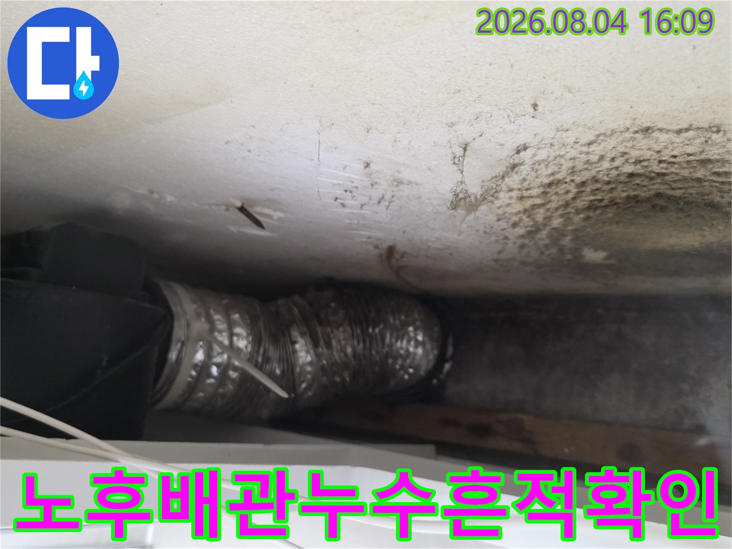 누수로 인해 변색된 천장면과 노출된 배관을 검사하는 사진