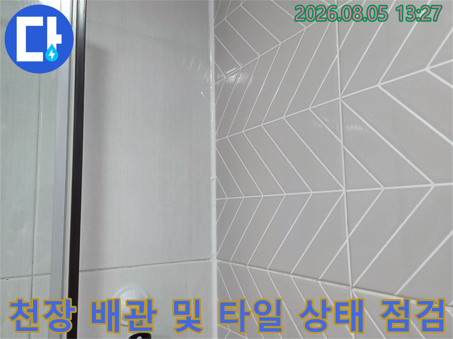 흰색 기하학적 패턴이 있는 화장실 천장과 노출된 수도 배관의 점검 모습