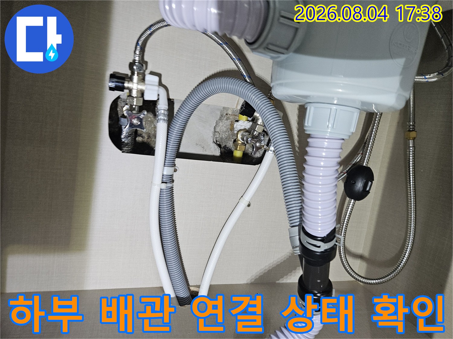 싱크대 아래 노출된 회색 주름관과 배관 밸브의 상세 모습