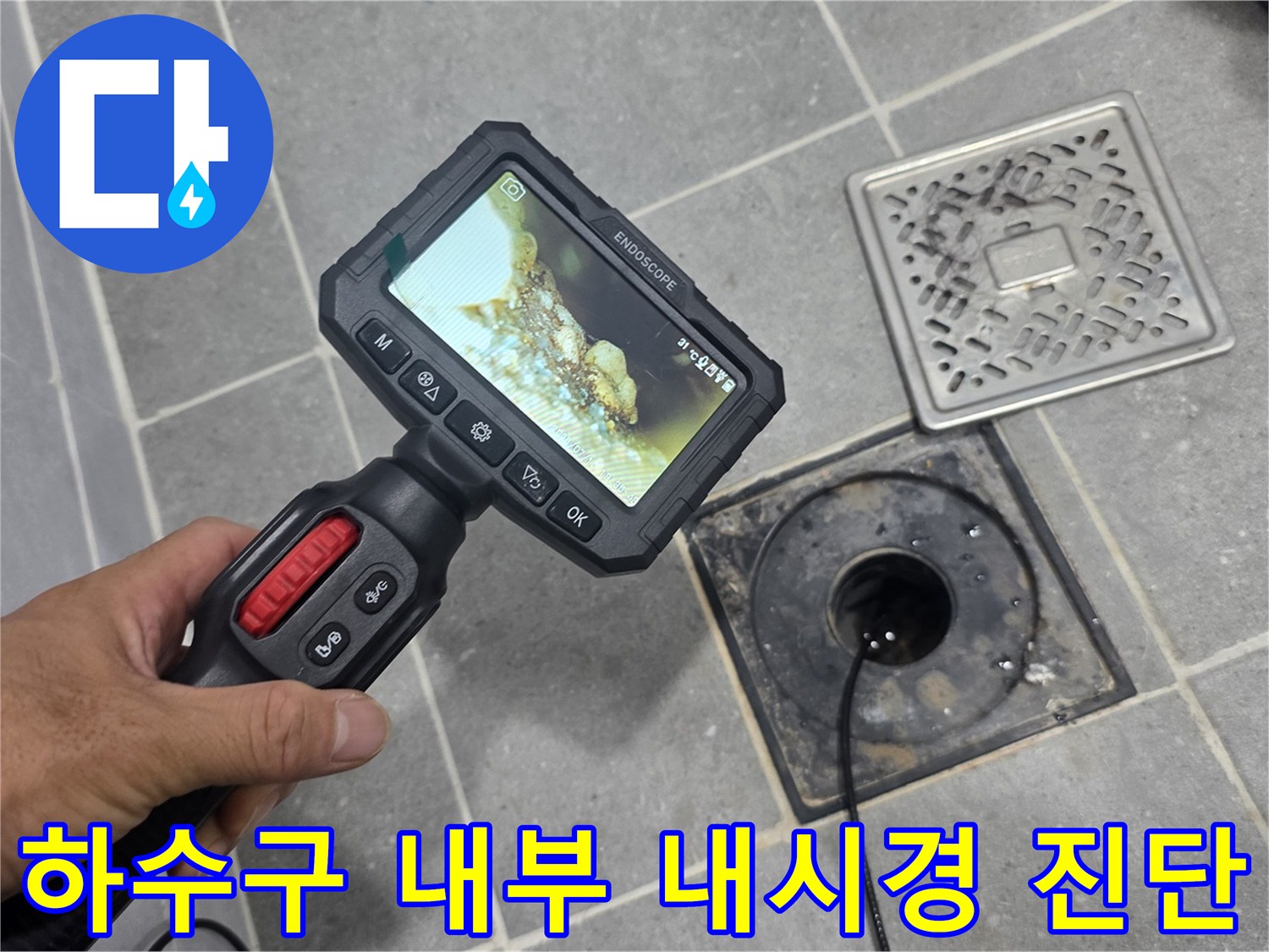 타일 바닥 배수구에 삽입된 내시경 카메라와 모니터 화면