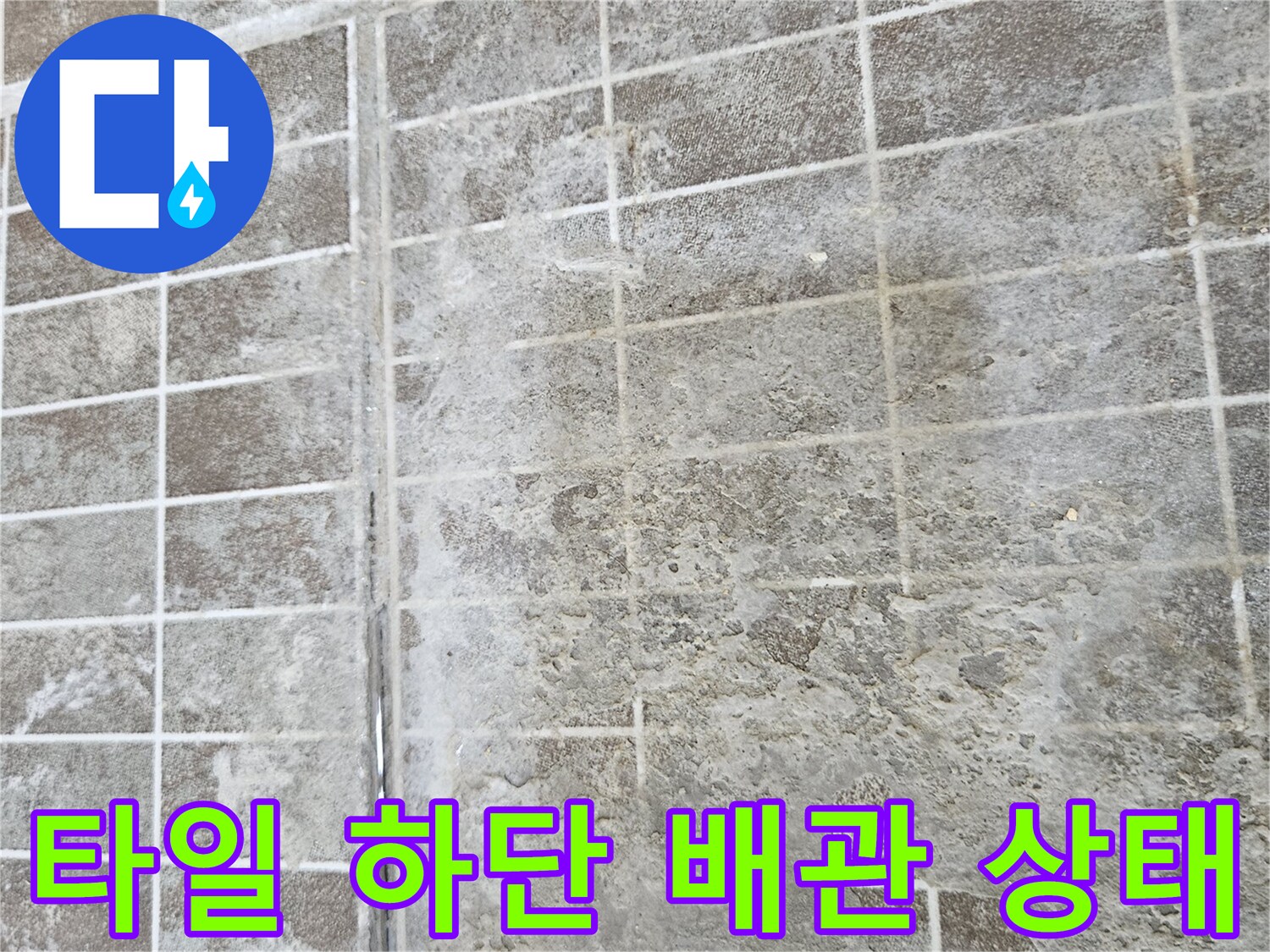 타일 격자 사이로 보이는 부식된 매립 배관