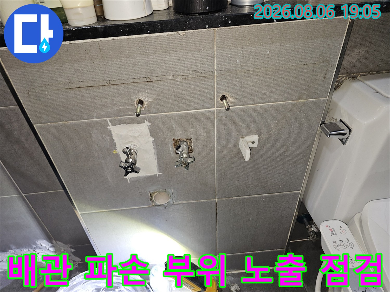 화장실 벽면 타일 제거 후 파손된 배관이 드러난 상태를 정밀하게 점검하는 현장