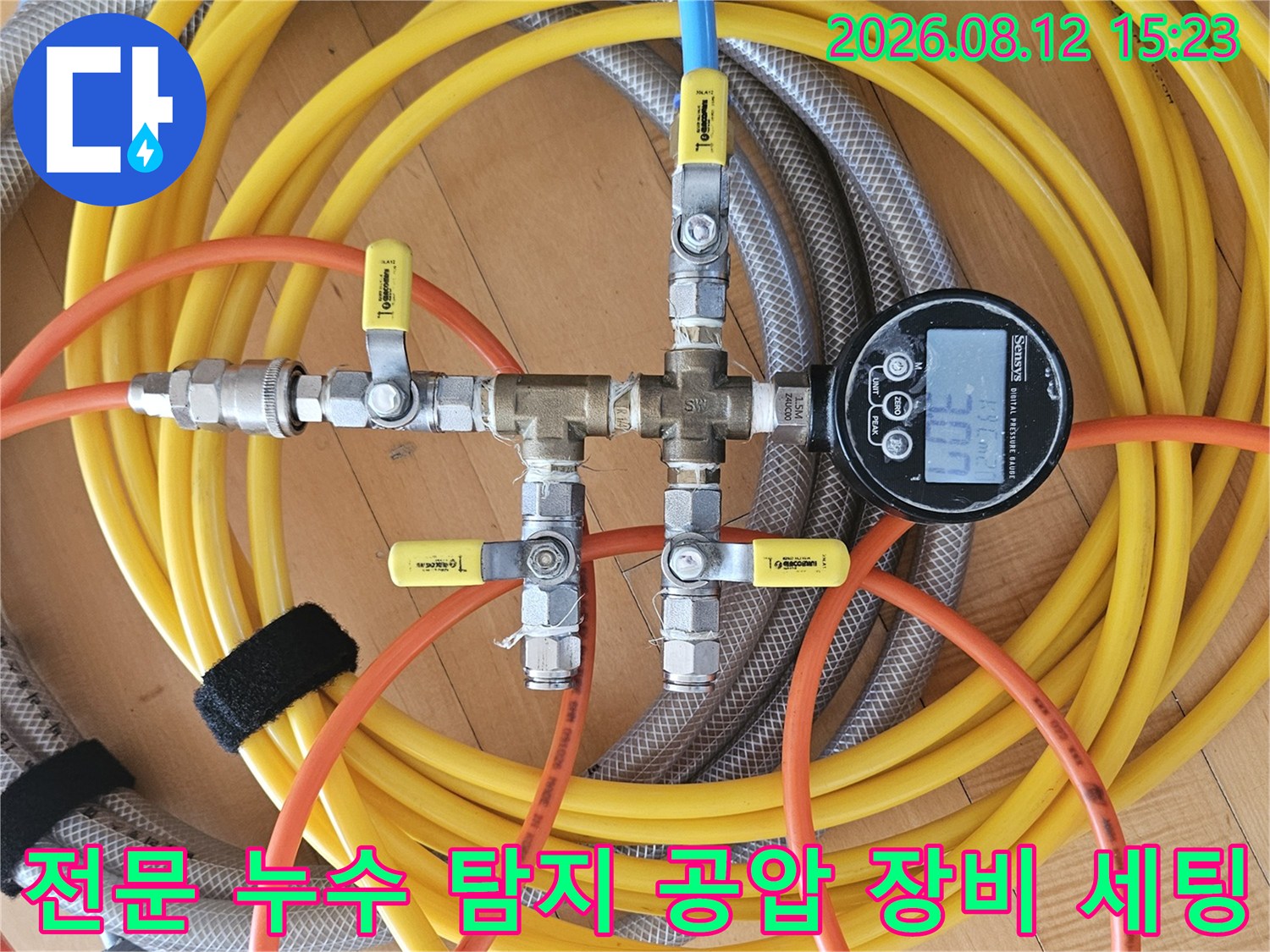 금속 밸브와 디지털 압력계 그리고 다채로운 색상의 호스가 연결된 모습