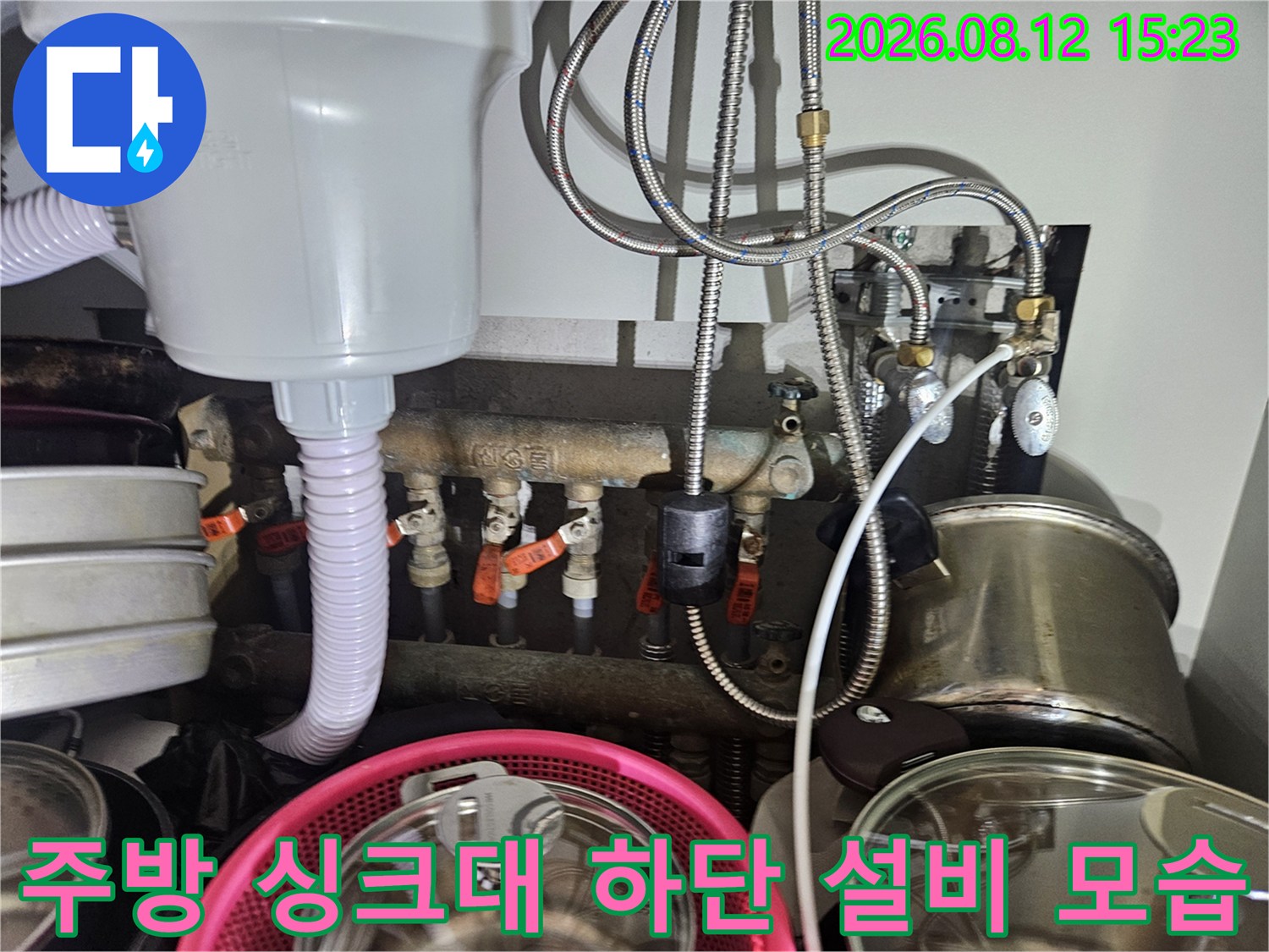 흰색 정수기 본체와 그 아래로 연결된 스테인리스 배관 및 붉은색 조절 밸브들