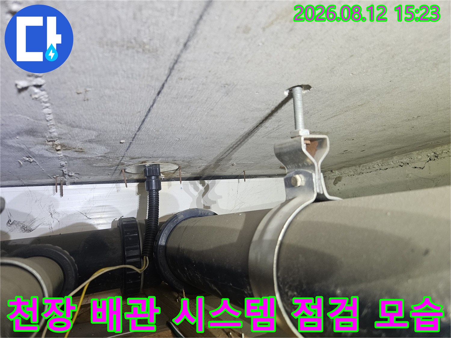 흰색 천장 슬라브 아래 설치된 검은색 하수관과 고정 장치-측면