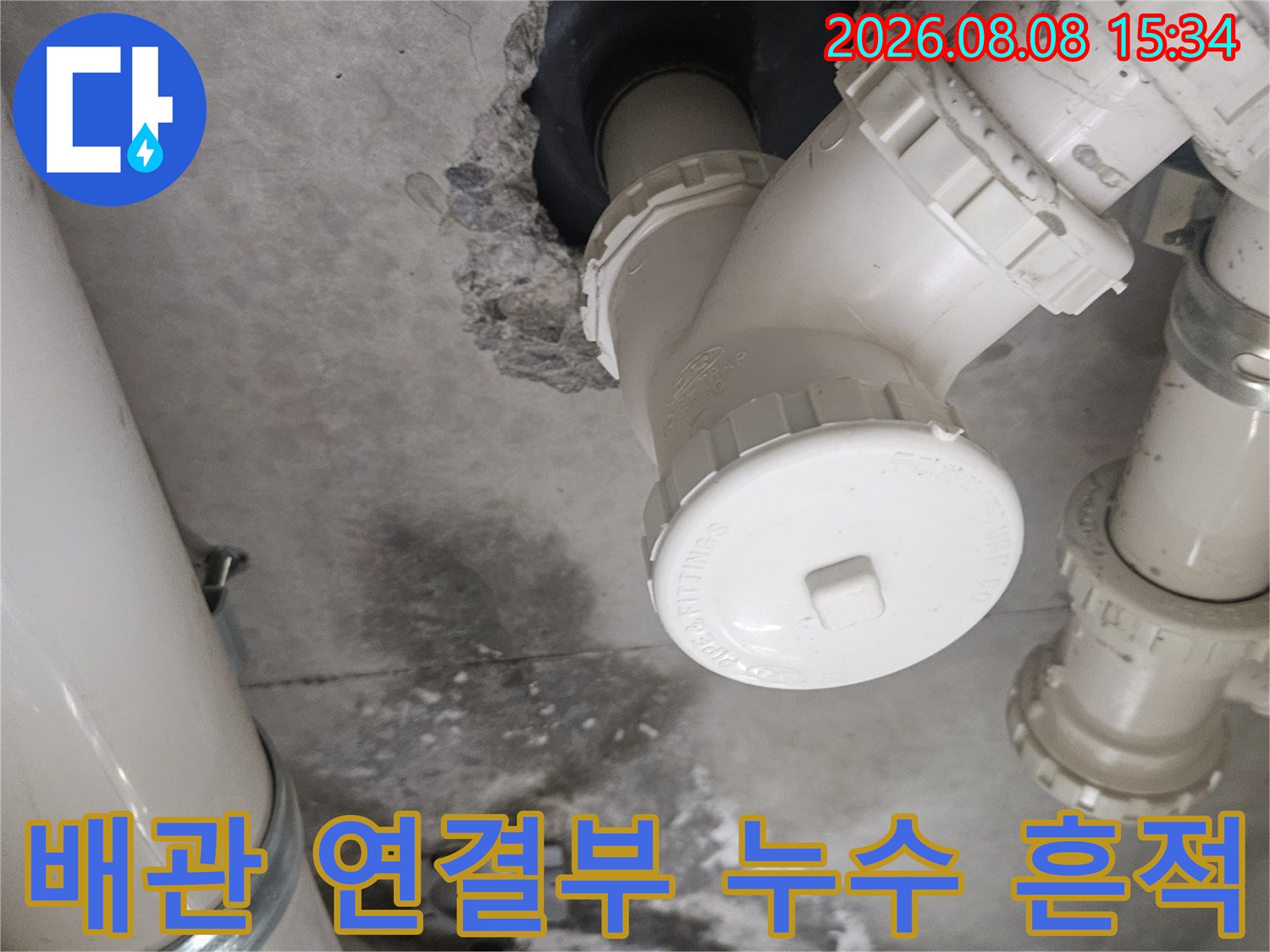 흰색 배관 연결 부위와 주변의 젖은 벽면을 촬영한 사진입니다.