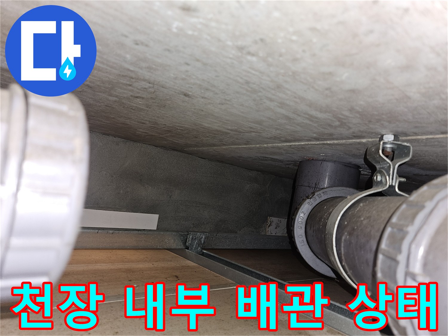 아파트 천장 내부의 검은색 배관과 고정용 클램프 모습