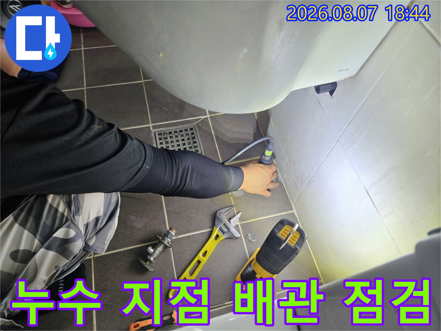 욕실 바닥 타일 틈새와 배관 연결부를 집중적으로 점검하는 공사 현장