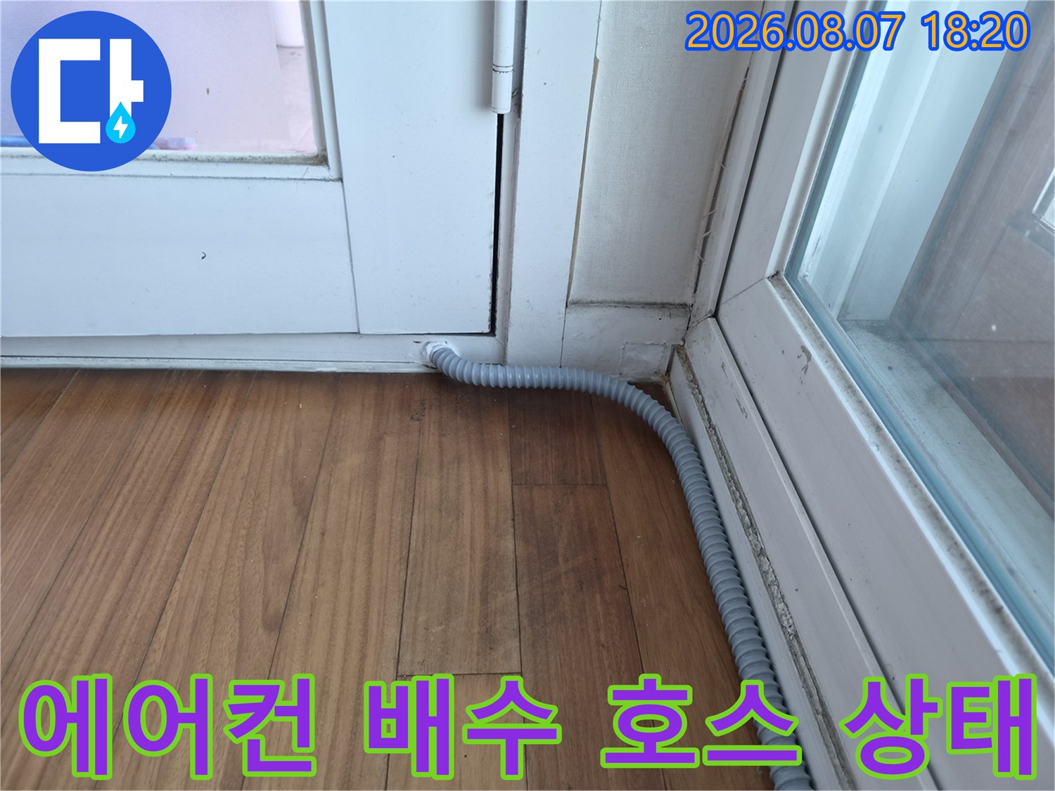 창문 하단에 위치한-회색 에어컨 드레인 호스의 모습입니다.