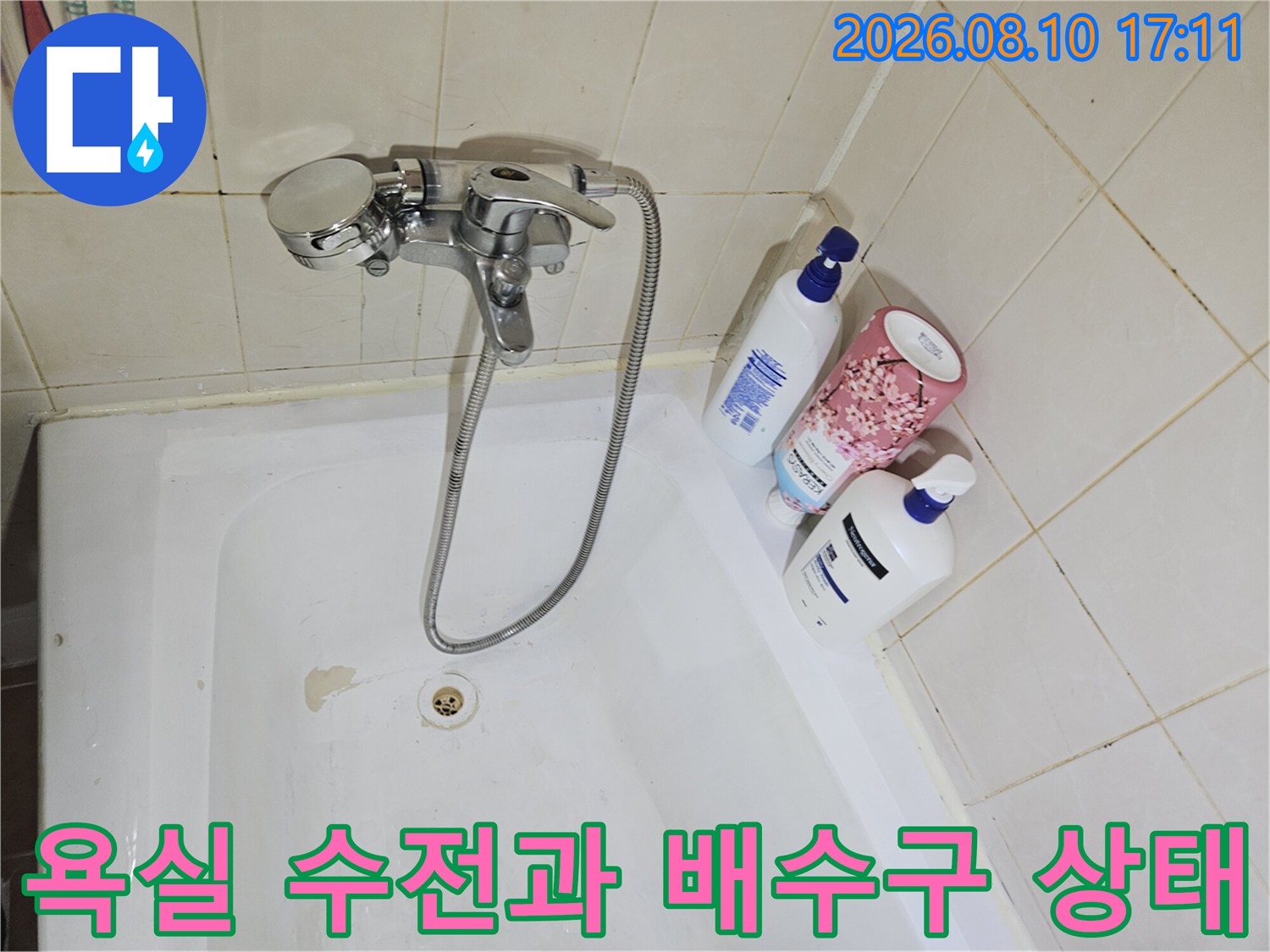 벽면 타일과 연결된 수도꼭지 및 욕조 내부 배수구의 모습입니다.