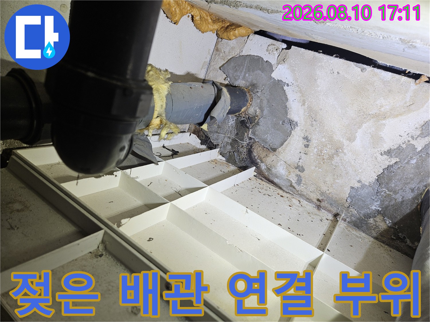 천장 내부 배관 주위의 젖은 벽면과 얼룩진 상태를 나타냅니다.