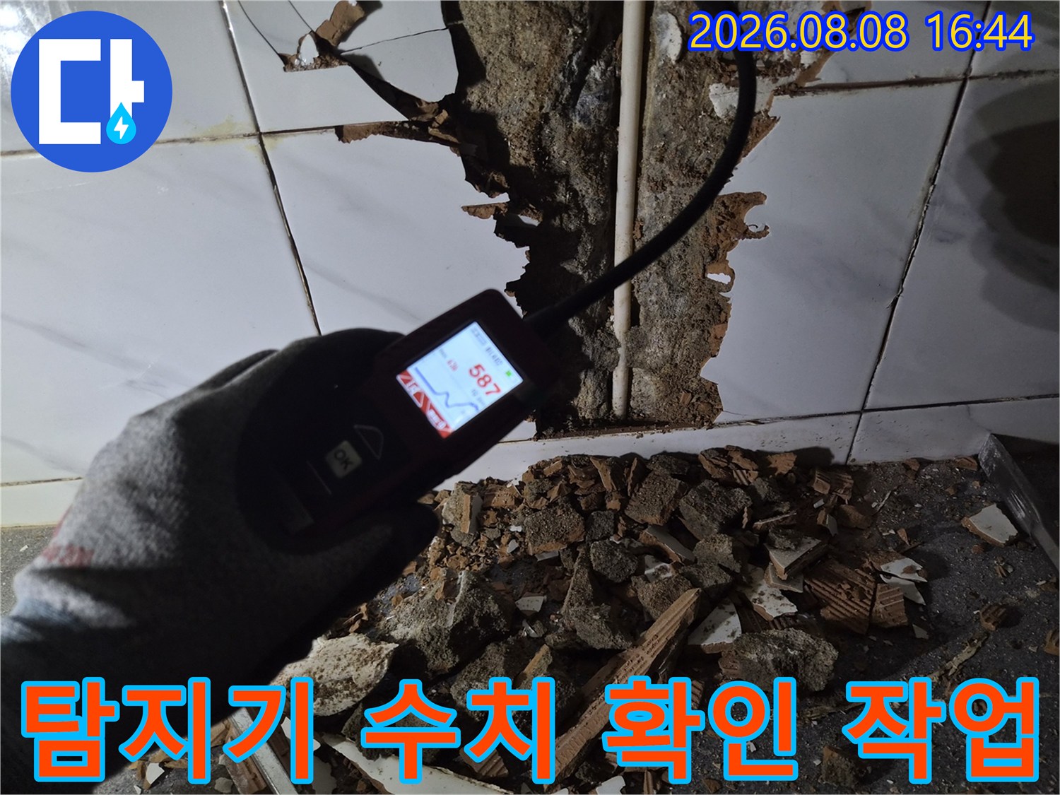 숫자가 표시된-가스 탐지기를 배관 근처에 대고 있는 손