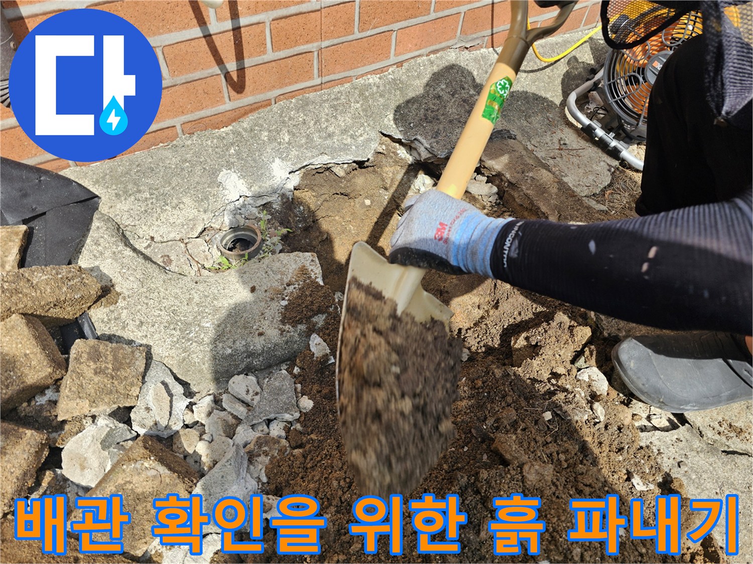 삽으로 흙과 콘크리트 잔해를 걷어내며 배관 근처를 드러내는 장면