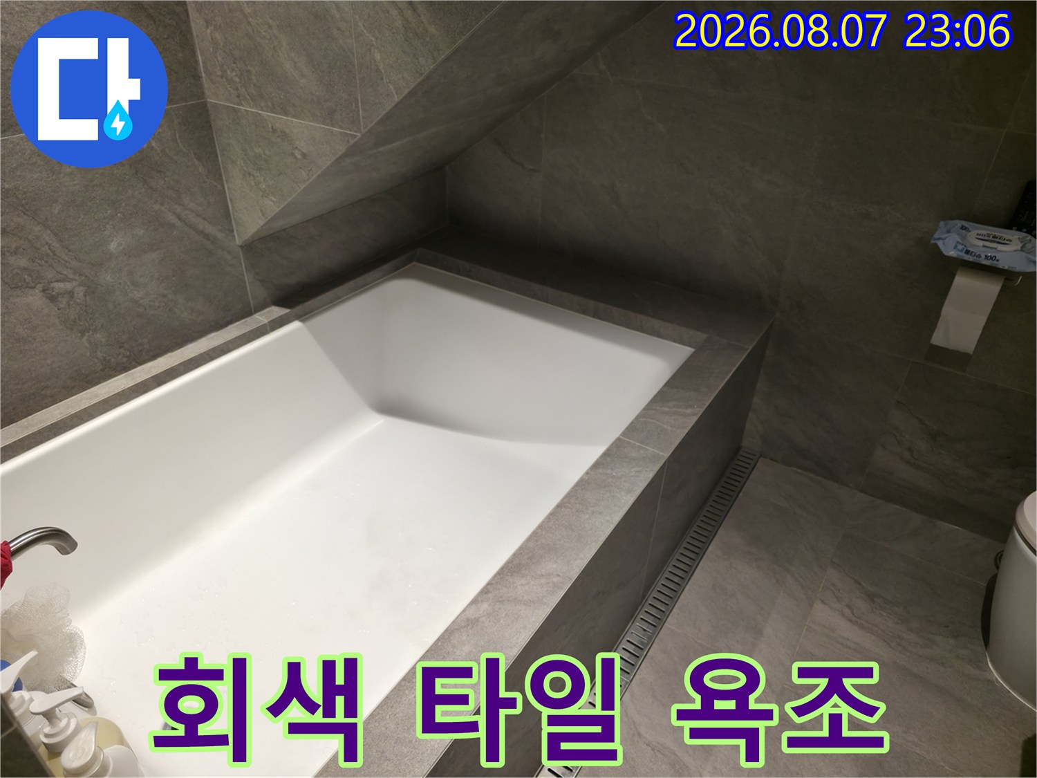 회색 톤의 고급스러운 타일과 흰색 욕조가 보입니다.