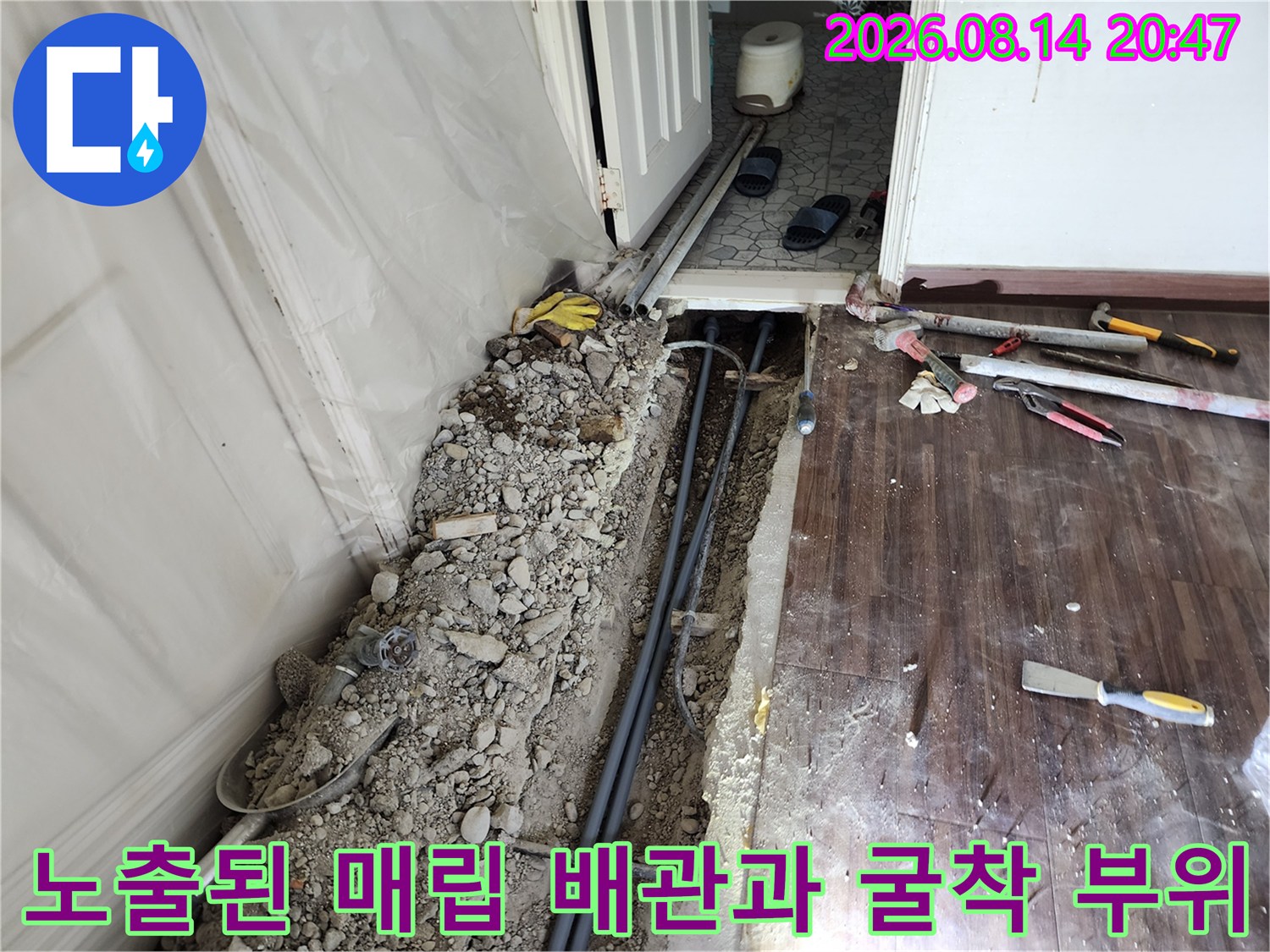 거실 마루 아래 굴착된 공간에 노출된 배관들의 현장 사진입니다.