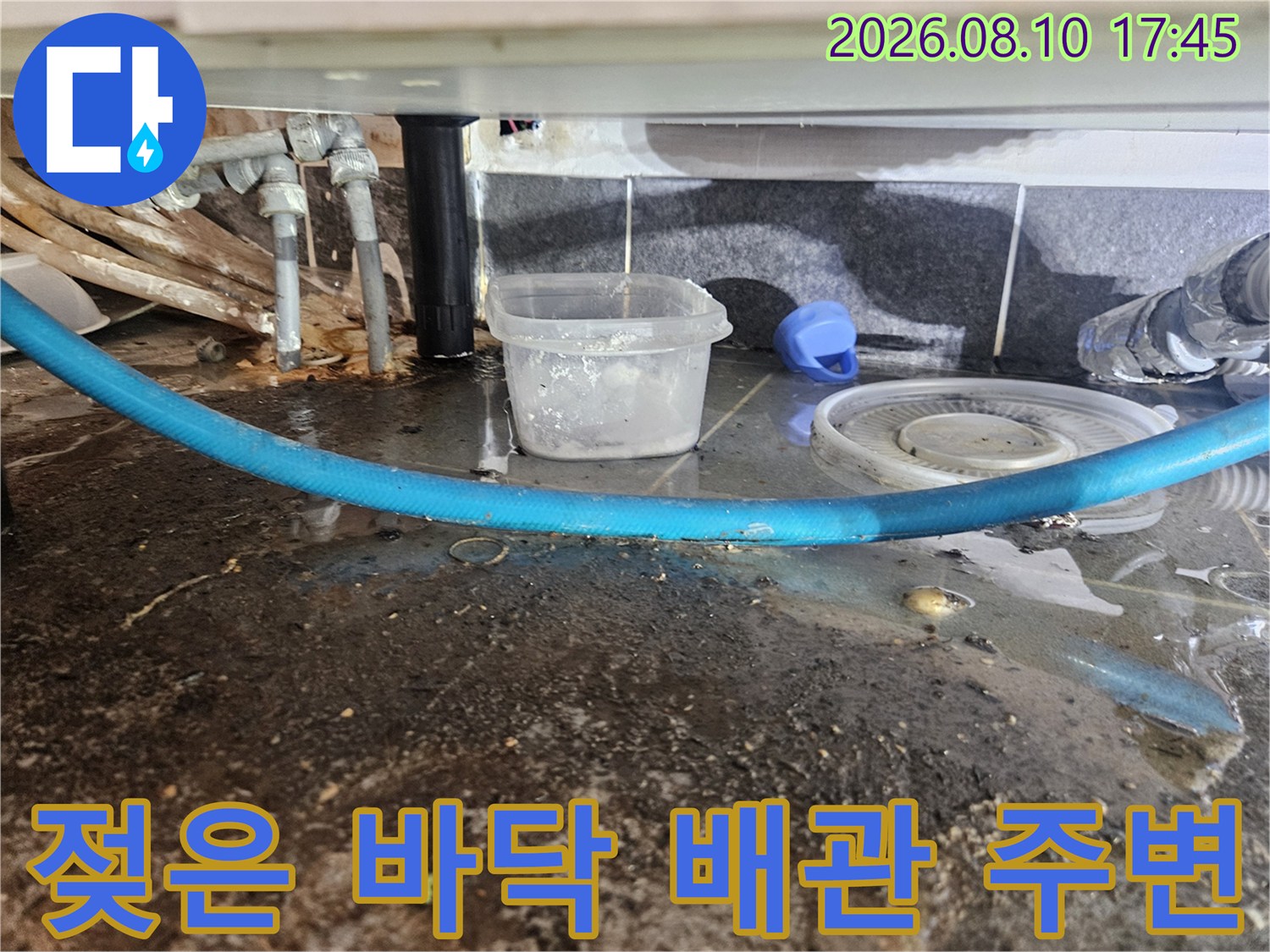 물기가 흥건한 바닥에 놓인 배관 및 호스 연결 부위 사진