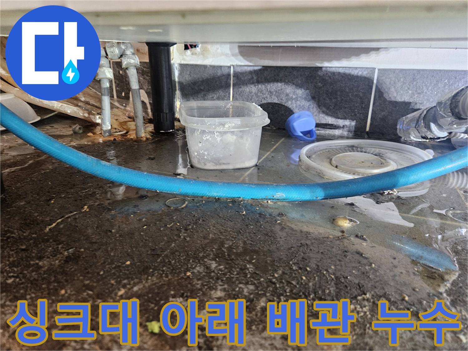 배수 호스 주변의 젖은 바닥과 배관 연결 부위