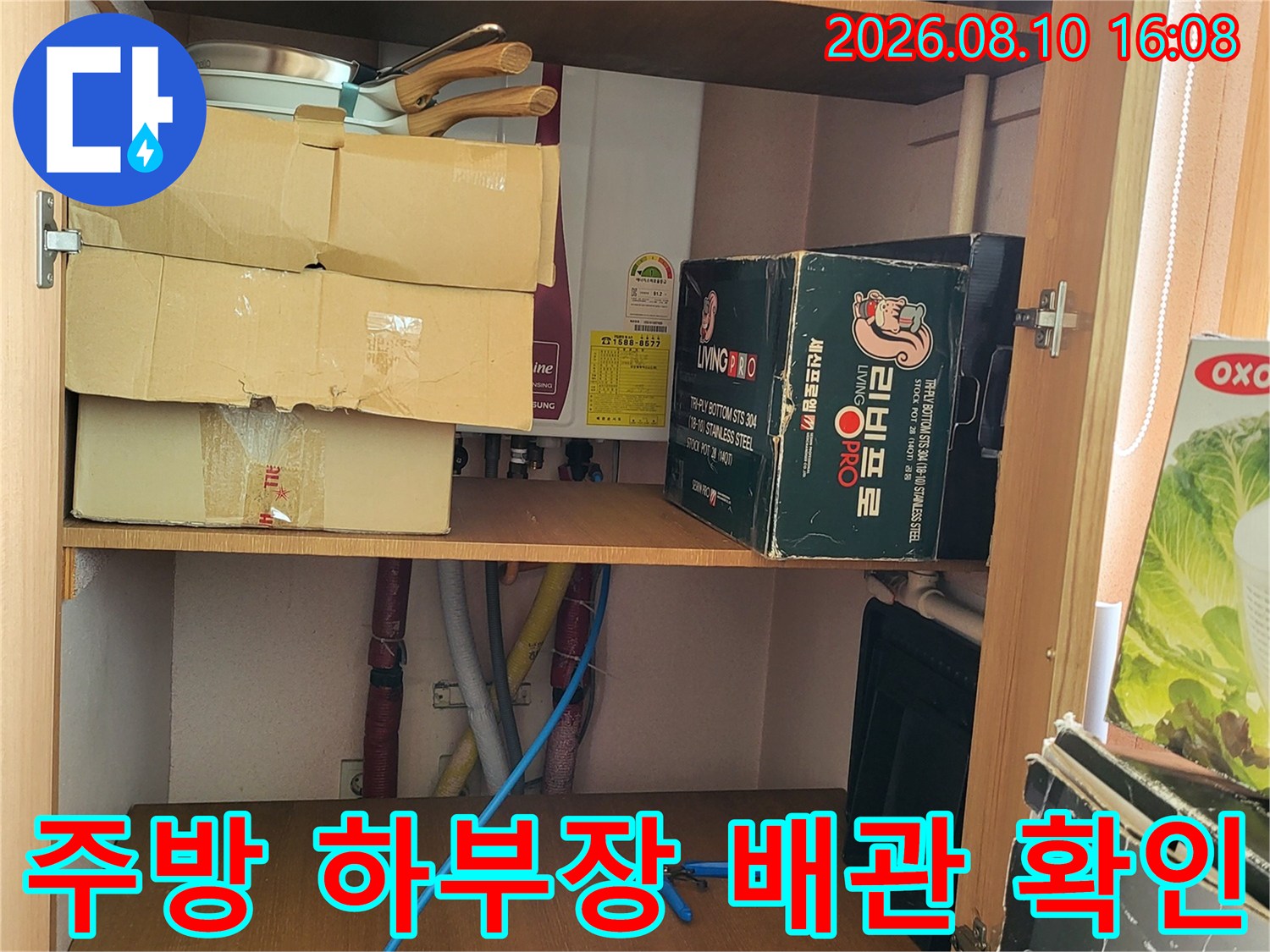 싱크대 아래 공간의 배관 연결 상태와 주변 물건들을 점검하고 있습니다.