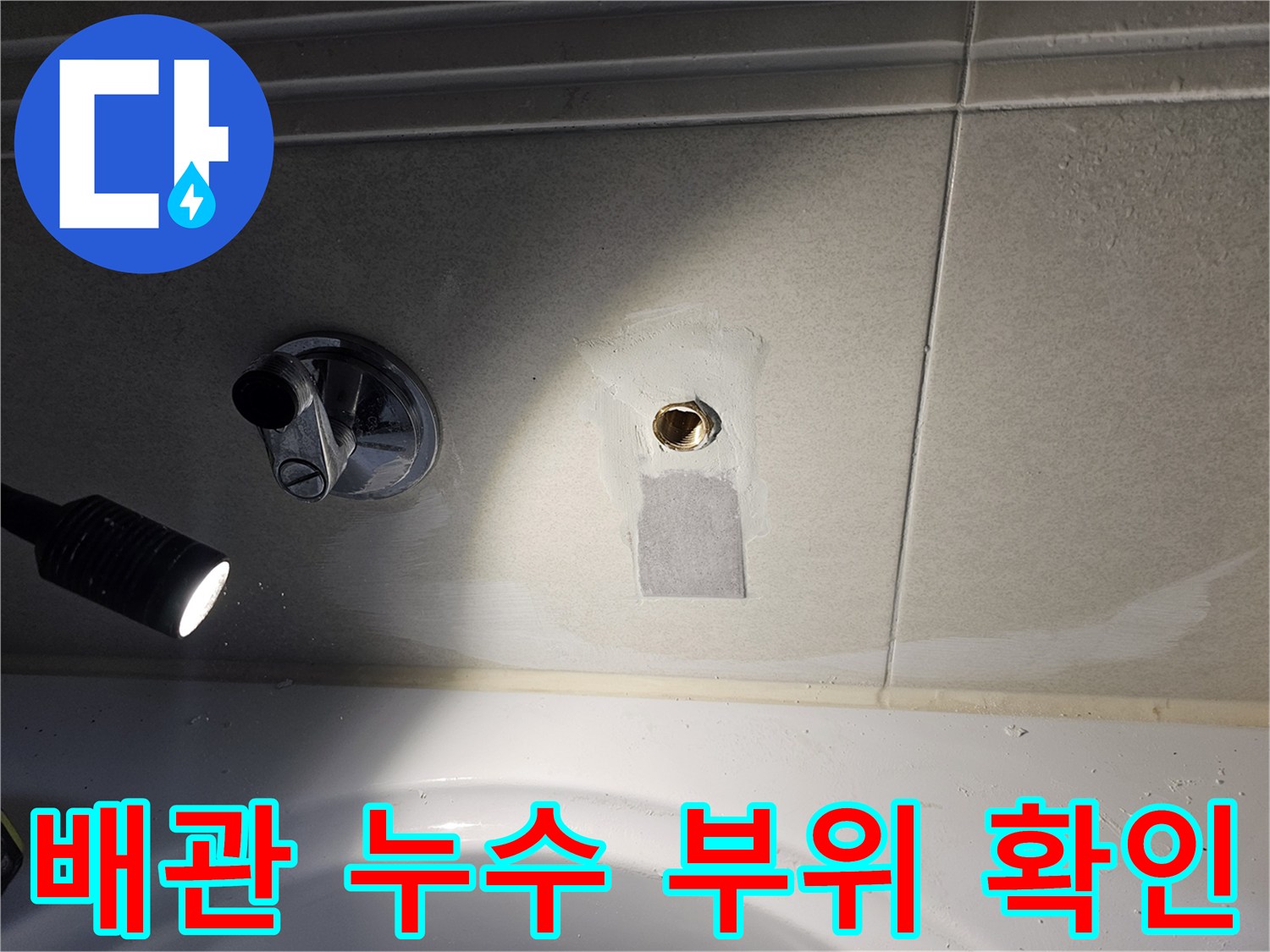 손전등으로 비추어 점검 중인 굴착된 벽면 배관 연결부