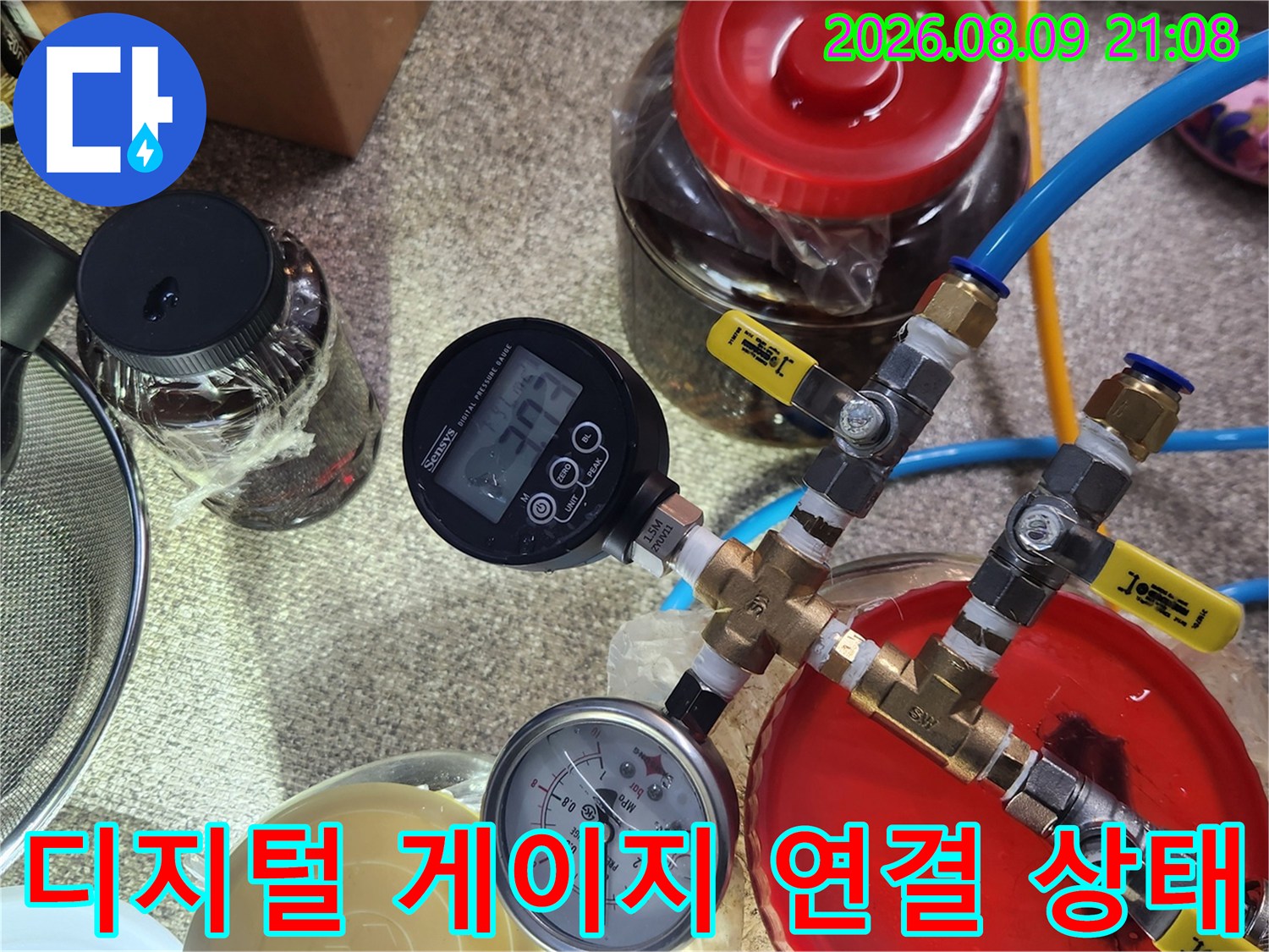 빨간색 뚜껑의 용기와-압력 측정 장비가 파란 호스로 연결된 모습