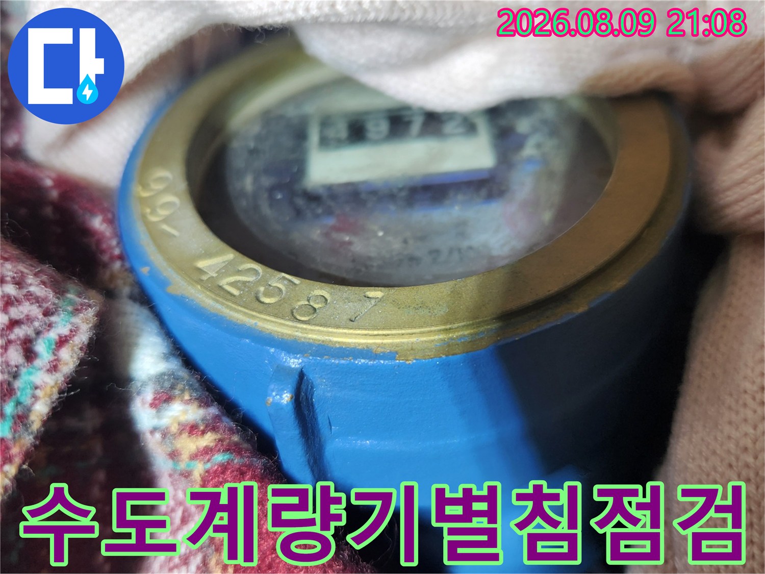 파란색 수도 계량기의 지시창과 그 위의 별침 부위를 촬영한 사진