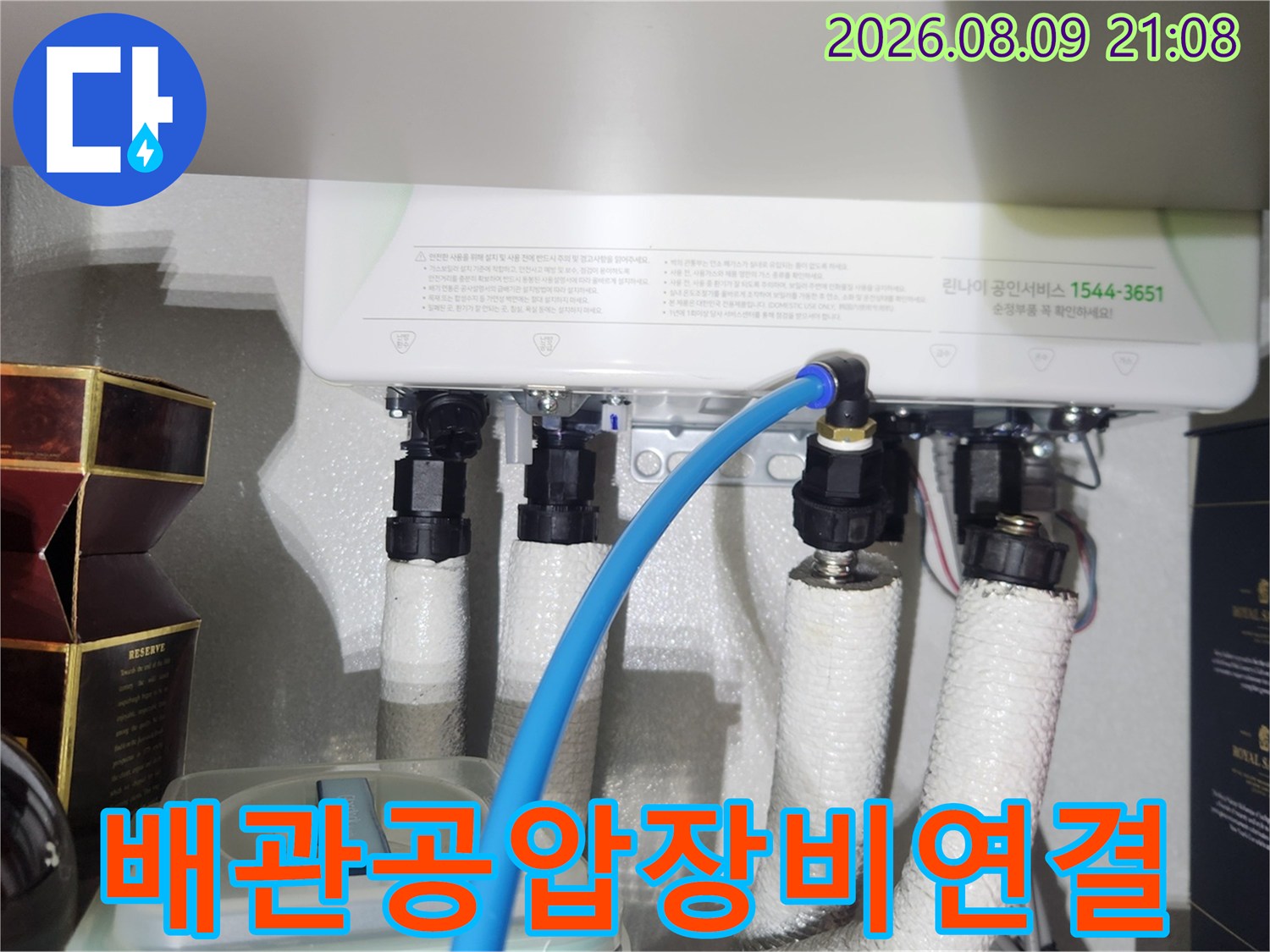 파란색 호스가 연결된 보일러 하단 직수 배관의 근접 사진