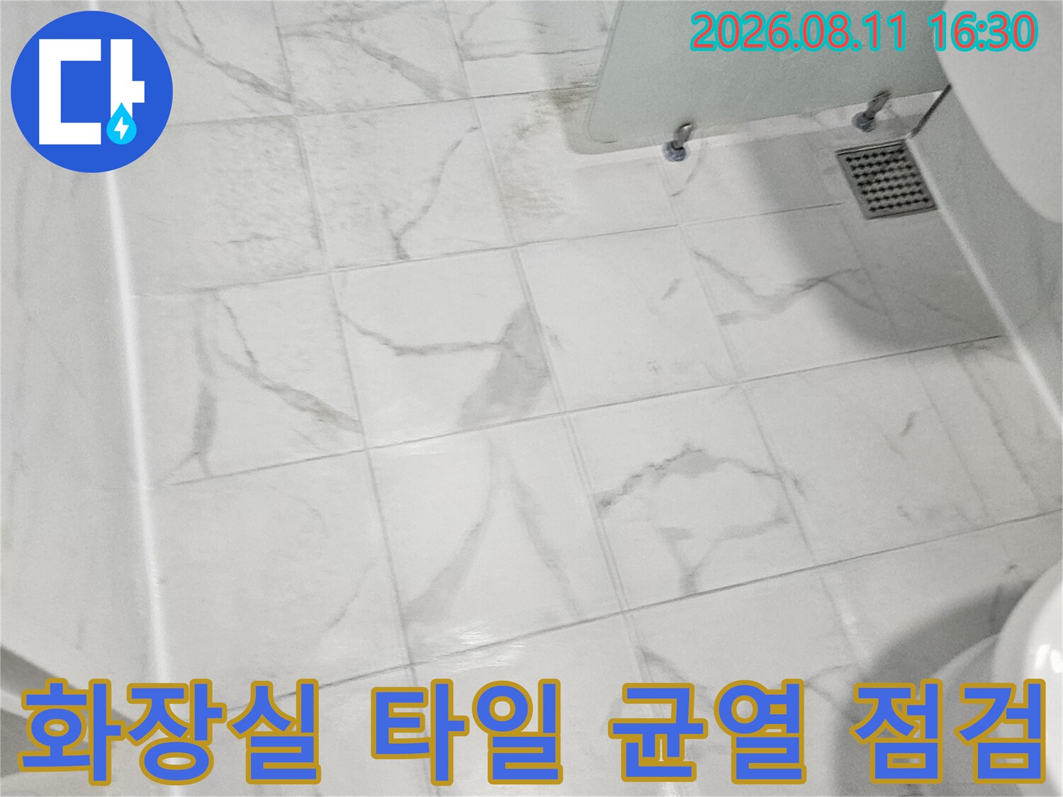 깔끔한 대리석 패턴의 화장실 바닥 타일과 배수구 덮개 부분입니다.