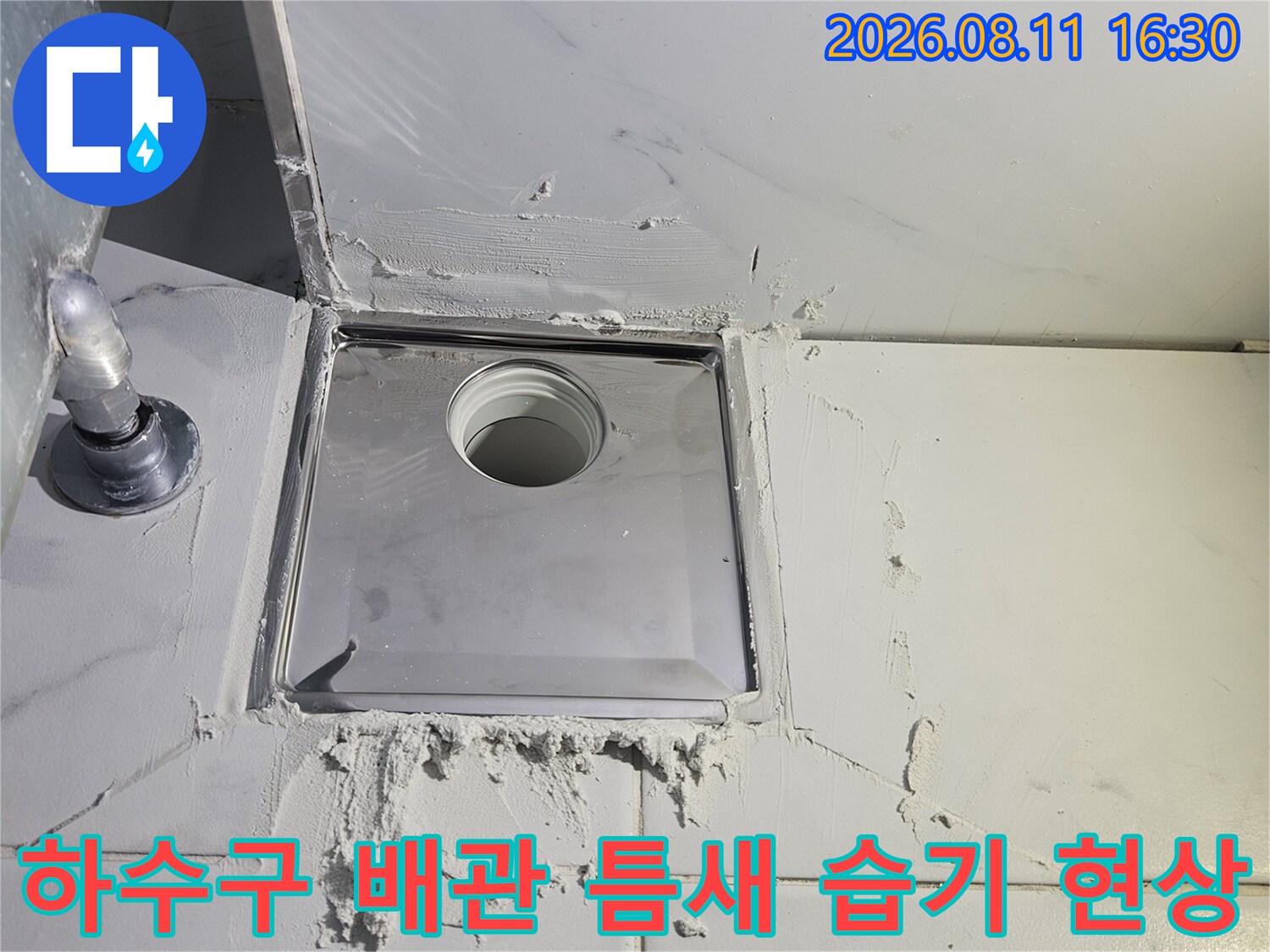 화장실 타일 벽면과 연결된 배수구 내부의 파손된 배관