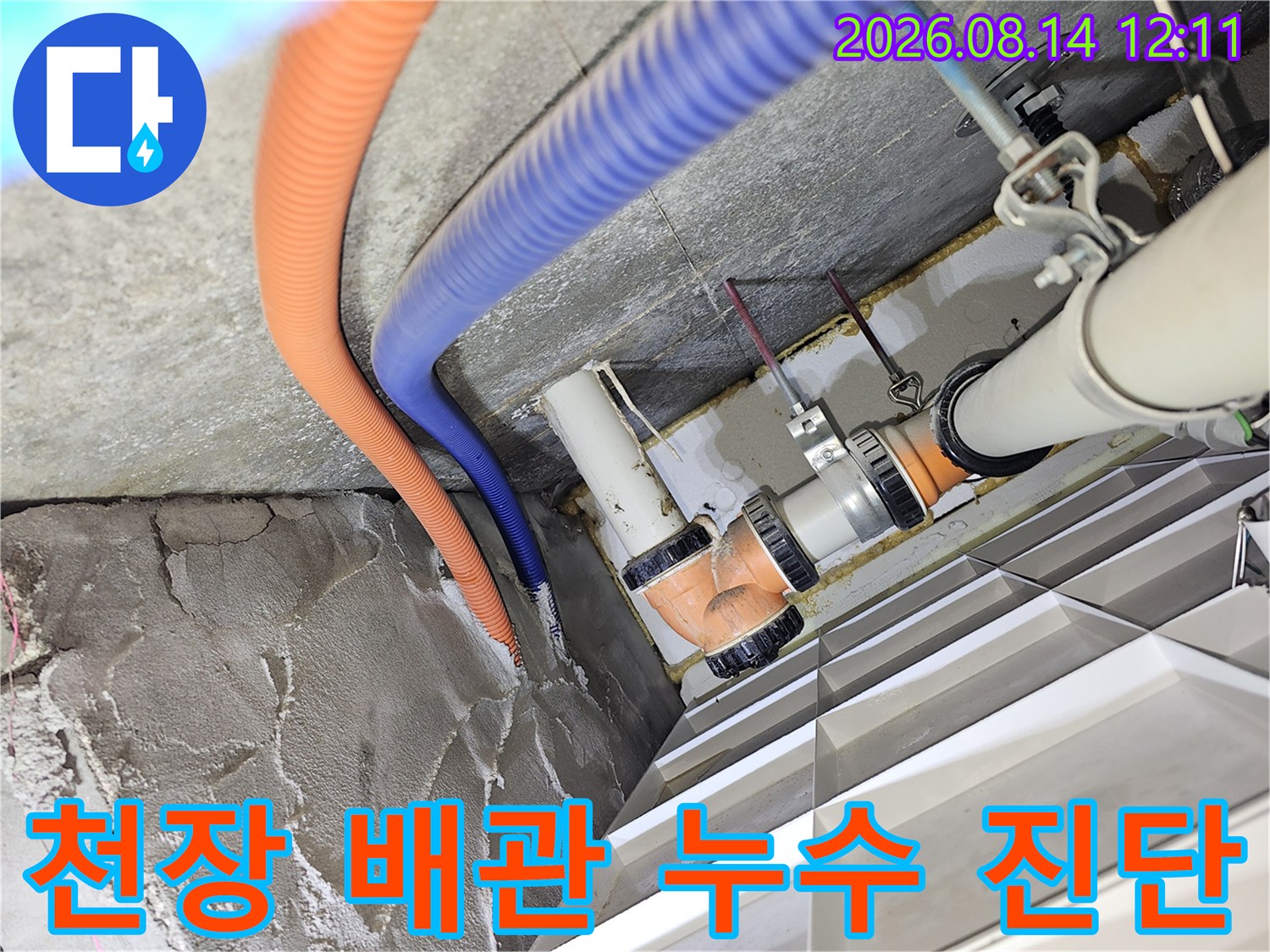 복잡한 천장 내부 배관 구조와 오렌지색 및 파란색 호스 연결 부위 사진입니다.