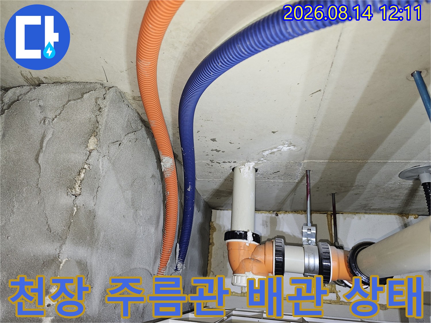 천장 내부의 오렌지색 및 파란색 주름관과 PVC 하수관이 보이는 현장