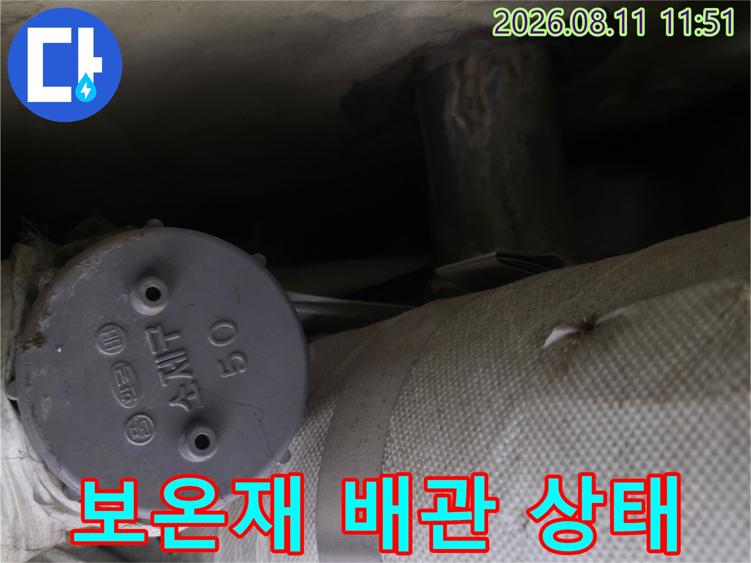 두꺼운 보온재로 감겨진 배관과 연결된 압력계의 근접 촬영입니다.
