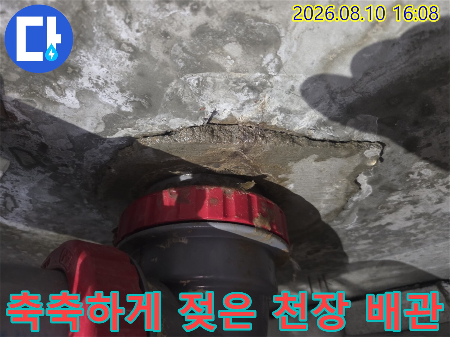 배관 연결 부위 주변의 젖은 콘크리트와 습기 흔적입니다.