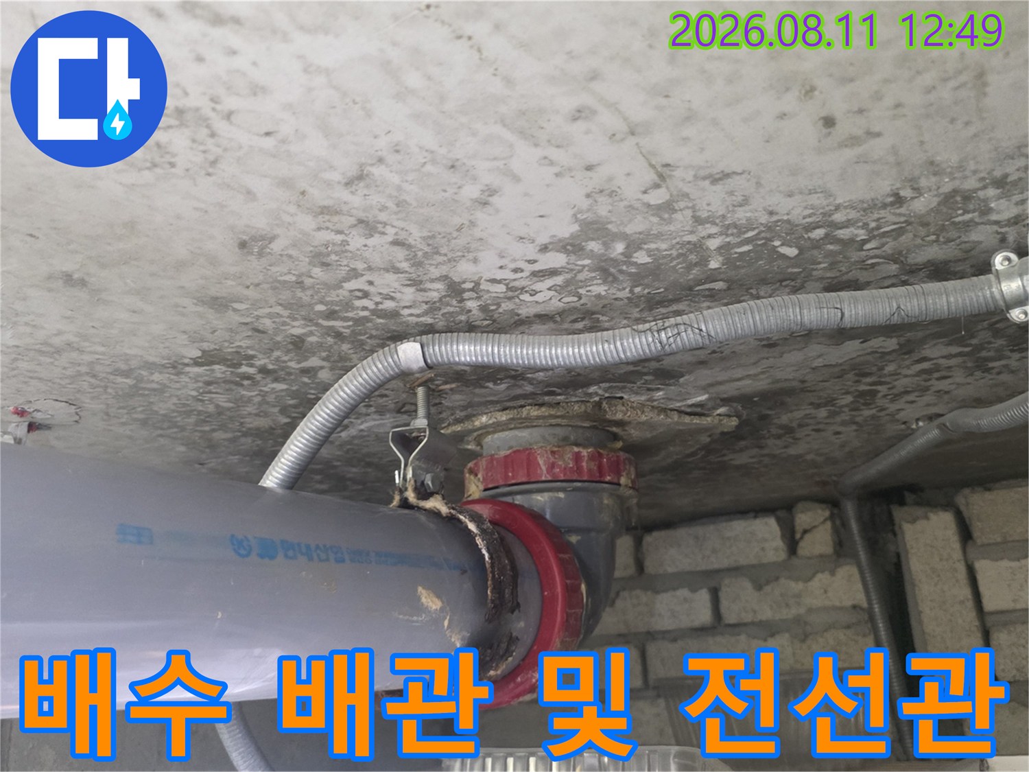 천장 배관 현장-굵은 배수관과 은색 자재의 연결 상태