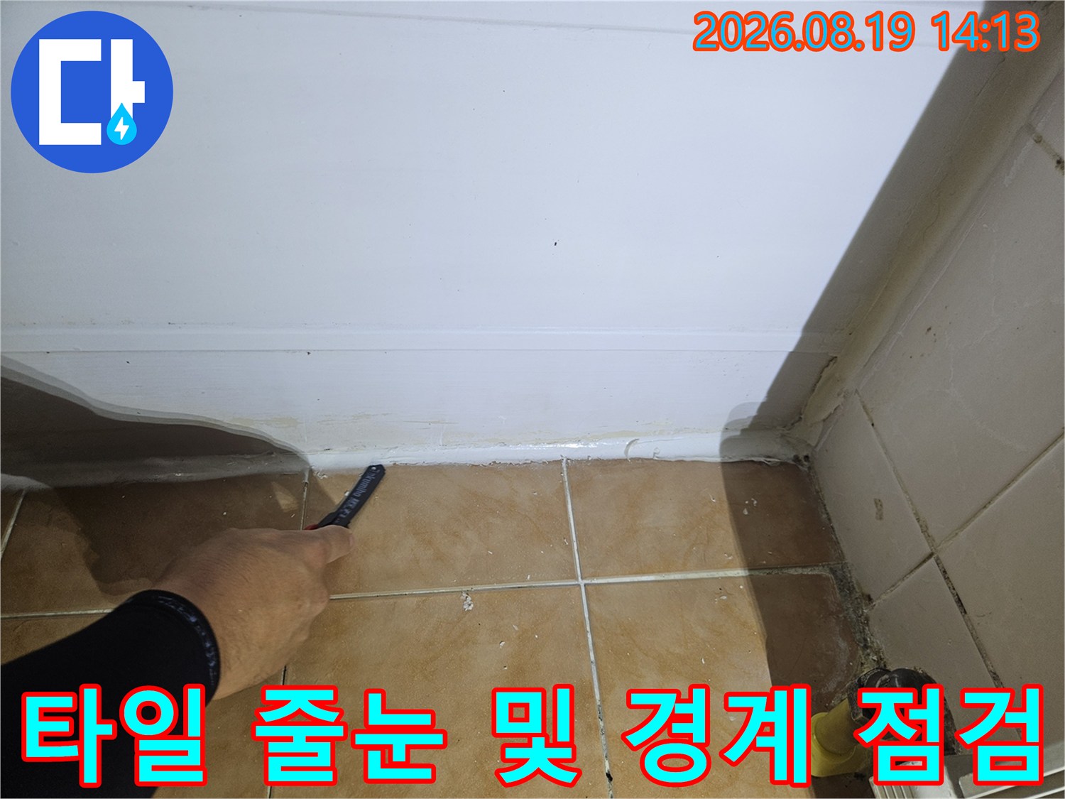 바닥 타일과 벽면 경계선의 메지 상태를 확인하는 장면