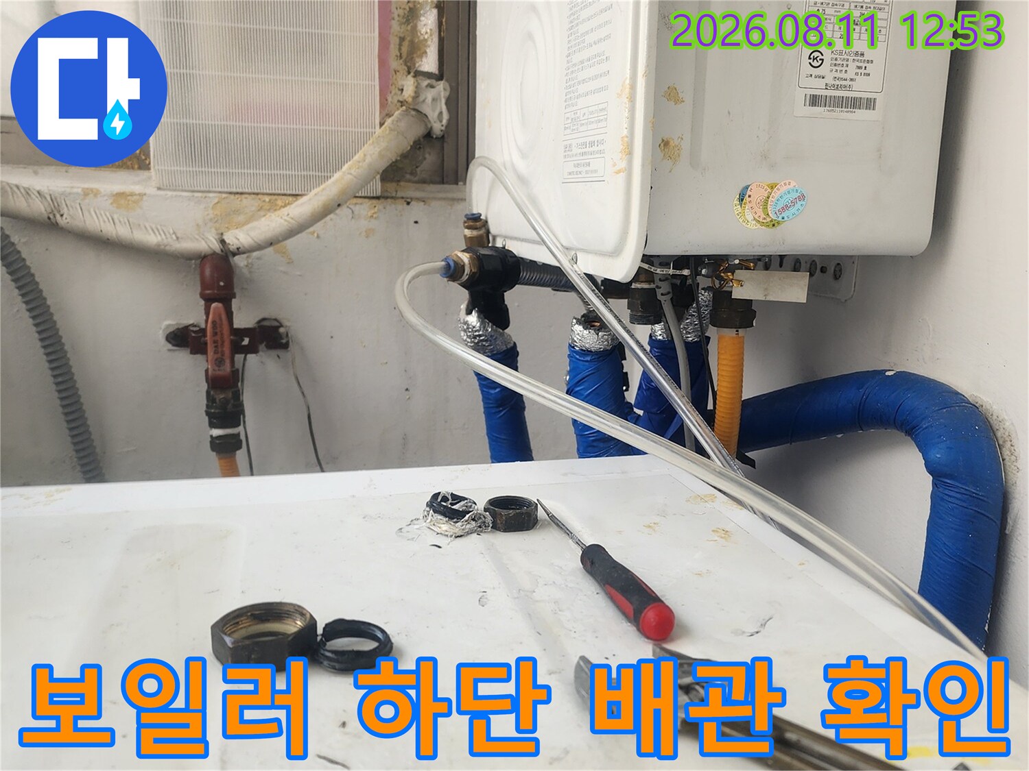 보일러 아래쪽 파란색 배관과 밸브 부위를 살펴보는 모습입니다.