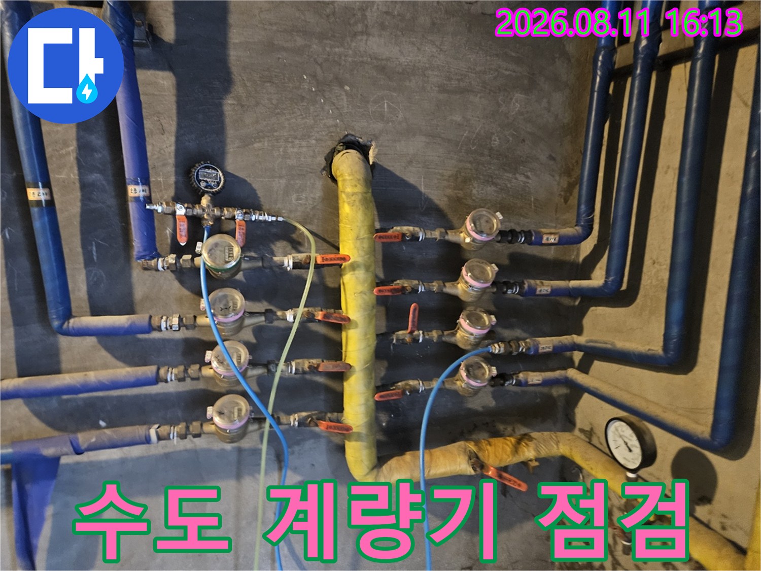 여러 갈래로 나뉜 수도 배관과 개별 계량기가 설치된 벽면 모습