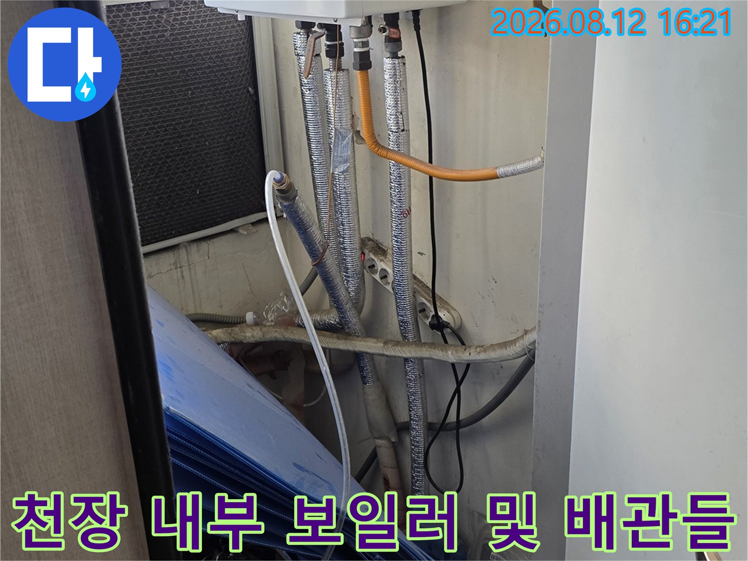 흰색 장비와 연결되어 수평으로 길게 뻗은 은색 단열재 배관들의 천장 내부 모습