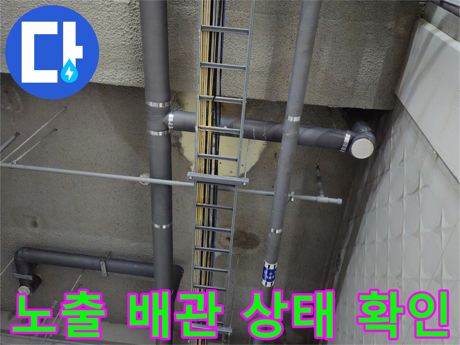 지하 주차장 천장에 설치된 회색 PVC 배수관과 전기 트레이