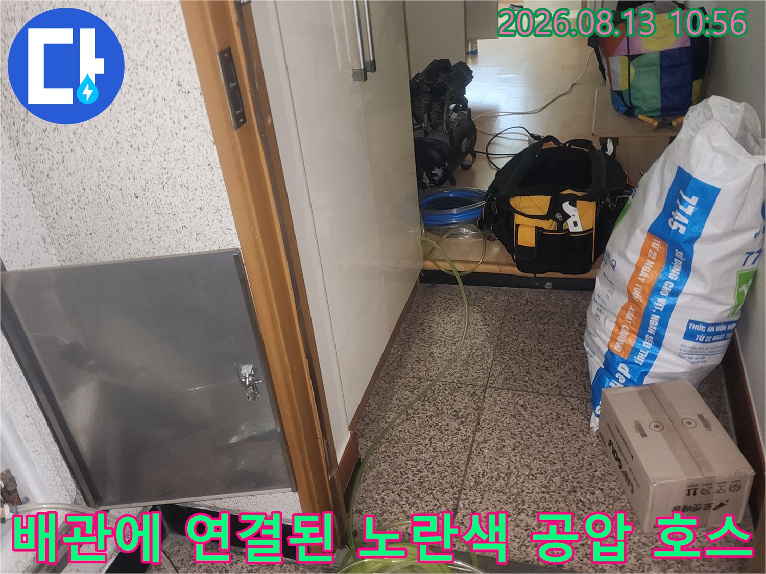 바닥 점검구 틈새로 누수 진단을 위한 노란색 호스와 측정 장비가 설치된 모습